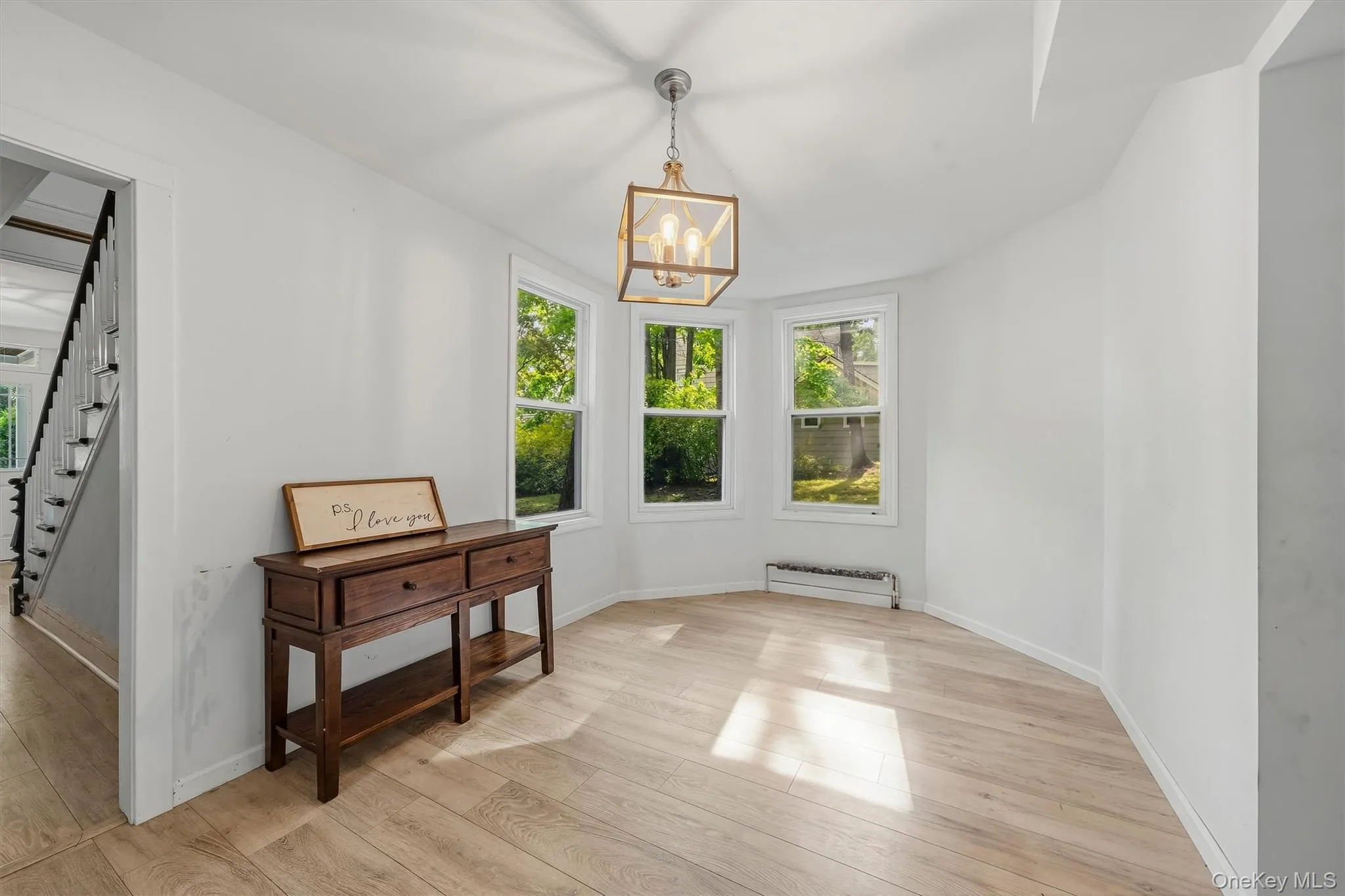 Light wood-finish flooring, white walls, three windows, and a ceiling-mounted light fixture Light wood-finish flooring, white walls, three windows, and a ceiling-mounted light fixture