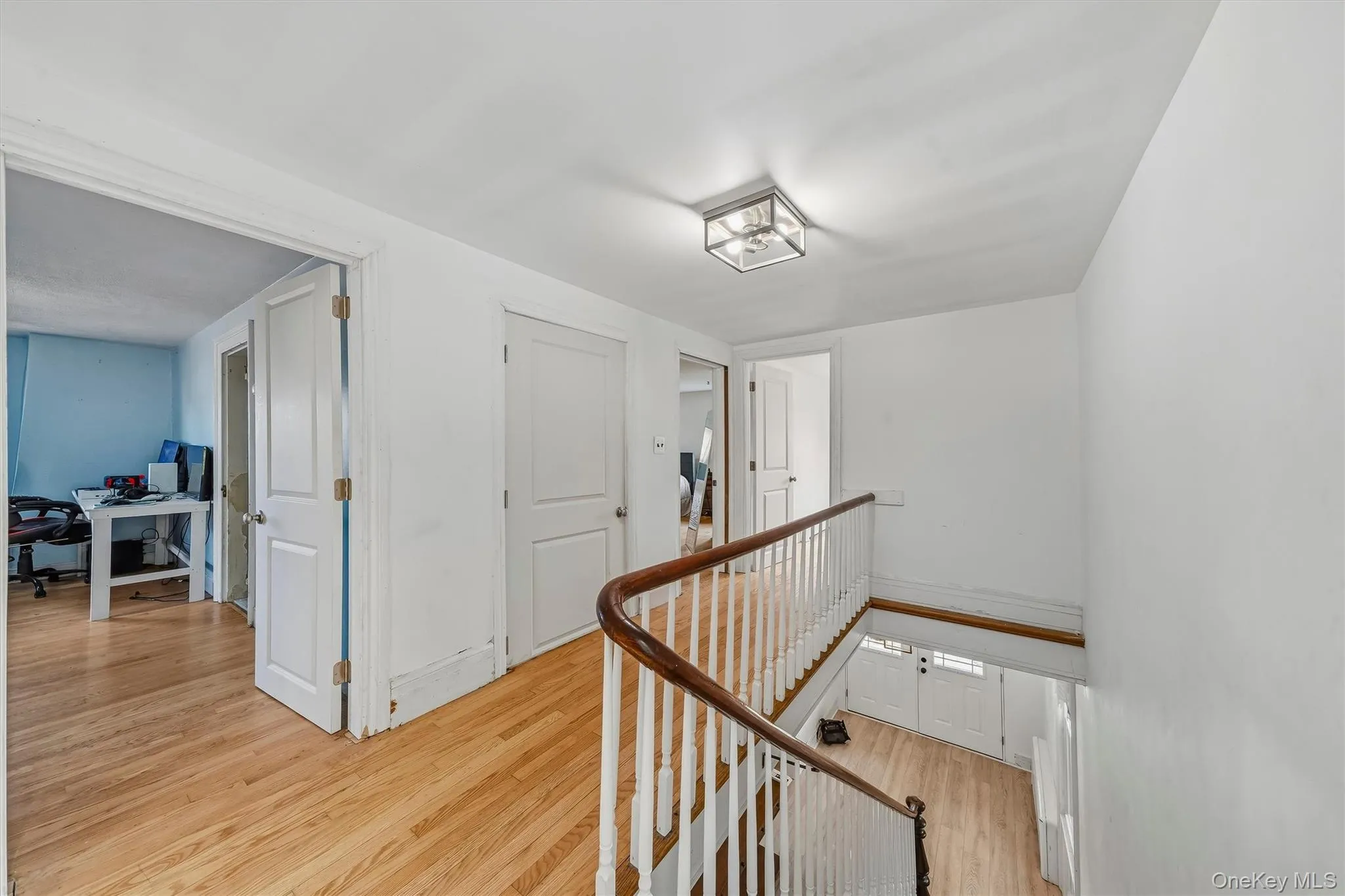 Hardwood flooring throughout, white walls, white doors, and a wood-finish handrail with white balusters Hardwood flooring throughout, white walls, white doors, and a wood-finish handrail with white balusters