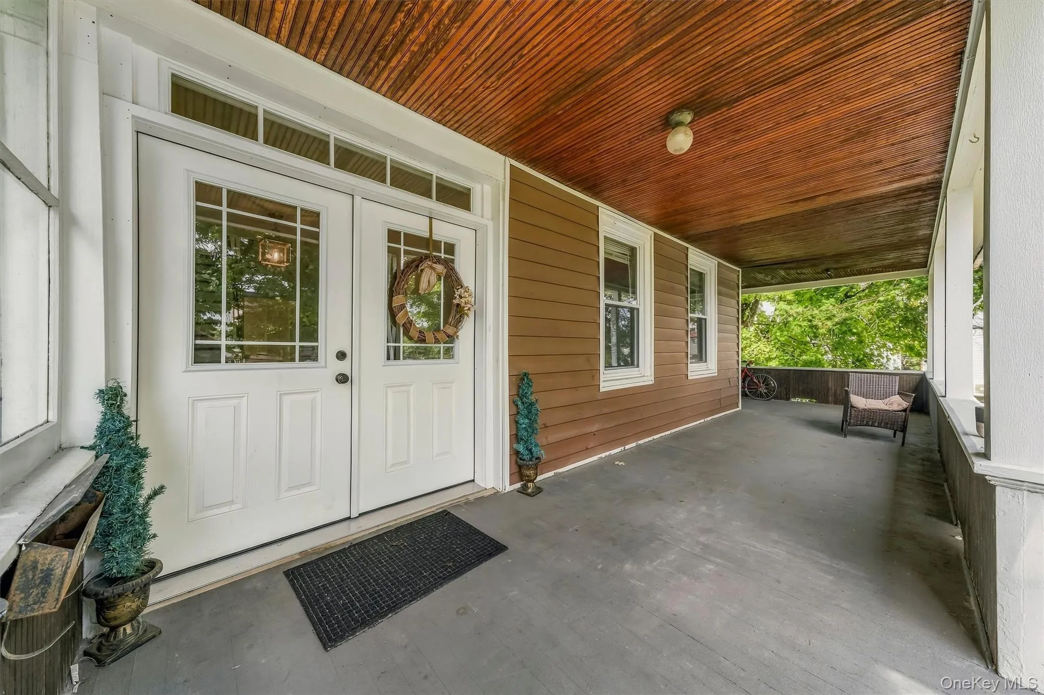 Covered porch featuring a wood-plank ceiling, white trim, and a gray floor Covered porch featuring a wood-plank ceiling, white trim, and a gray floor