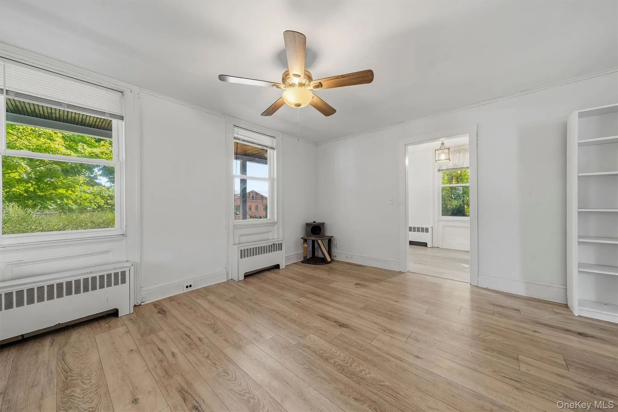 Wood-finish flooring, two windows with blinds, ceiling fan, and built-in shelving Wood-finish flooring, two windows with blinds, ceiling fan, and built-in shelving