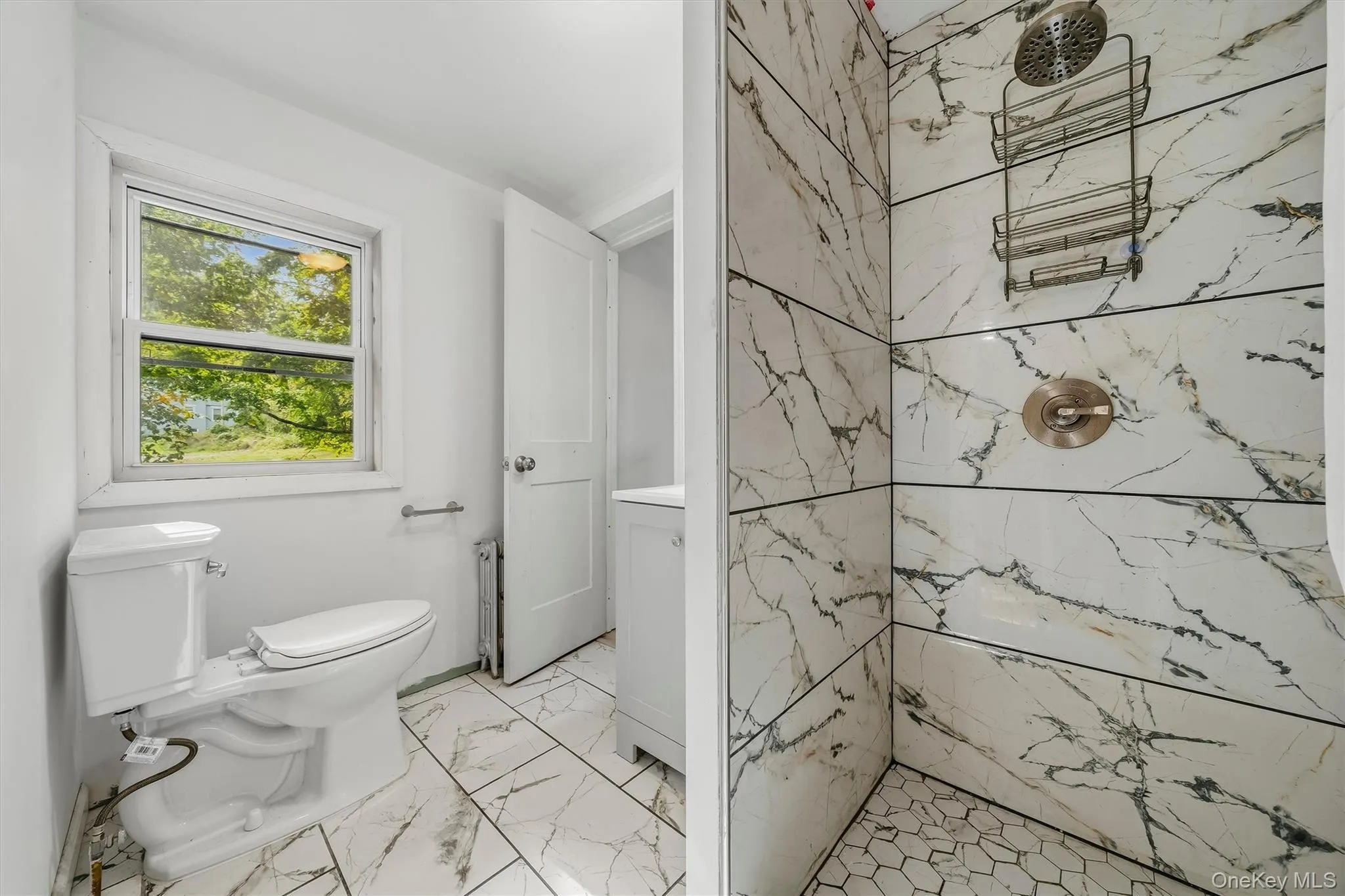 Bathroom featuring a tiled shower with a rain shower head, hexagonal floor tiles, and a window Bathroom featuring a tiled shower with a rain shower head, hexagonal floor tiles, and a window