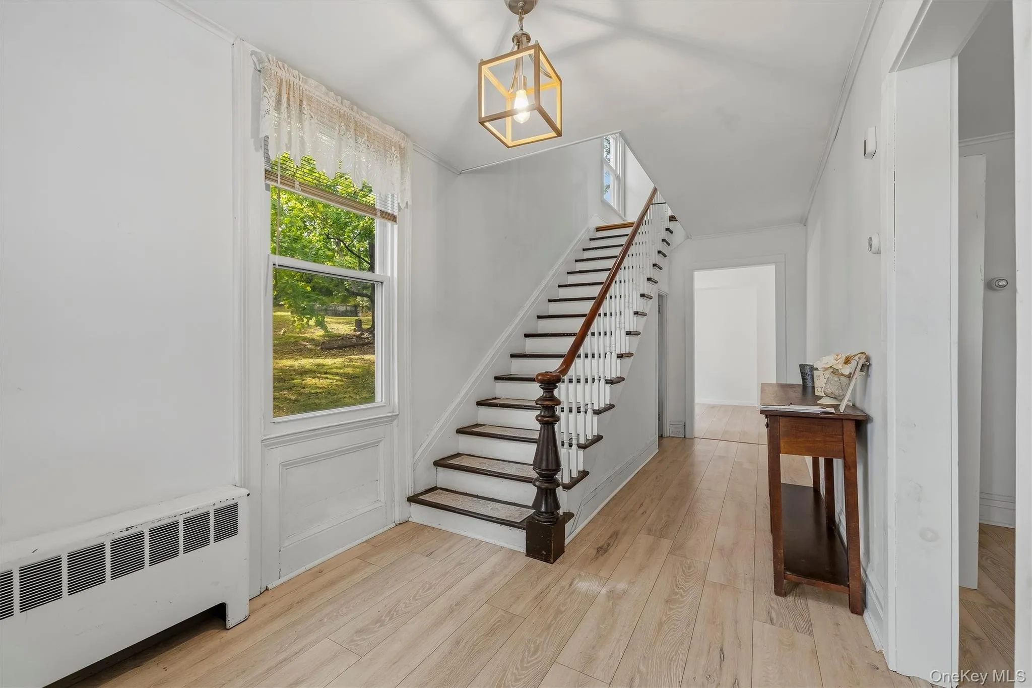 Bright entry hall with staircase, large window, and wood-look flooring. Bright entry hall with staircase, large window, and wood-look flooring.