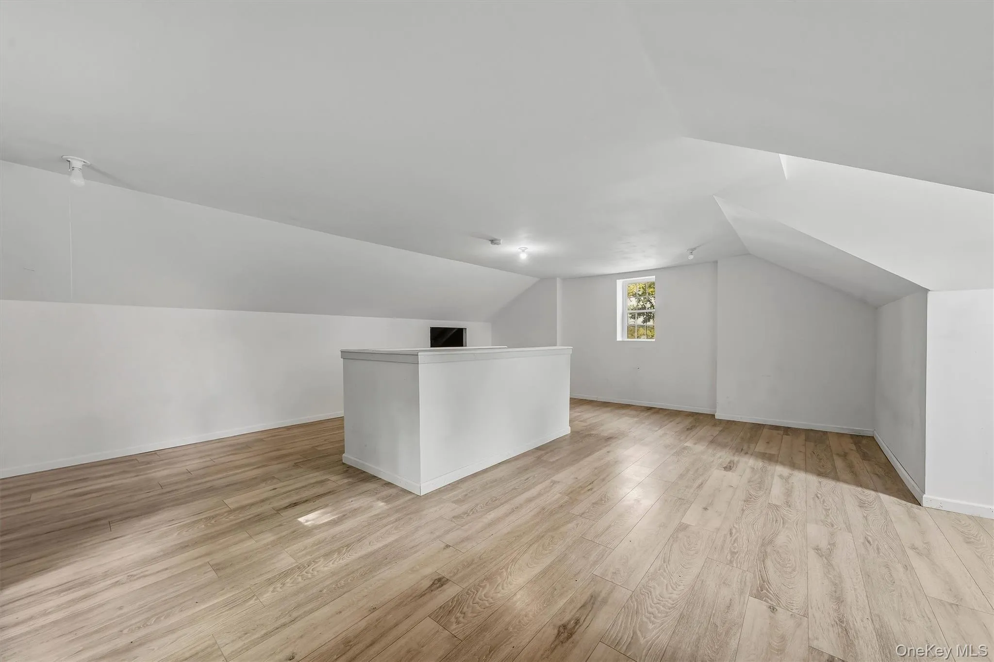 Spacious loft area featuring wood-finish flooring, recessed lighting, and a built-in half-wall partition Spacious loft area featuring wood-finish flooring, recessed lighting, and a built-in half-wall partition