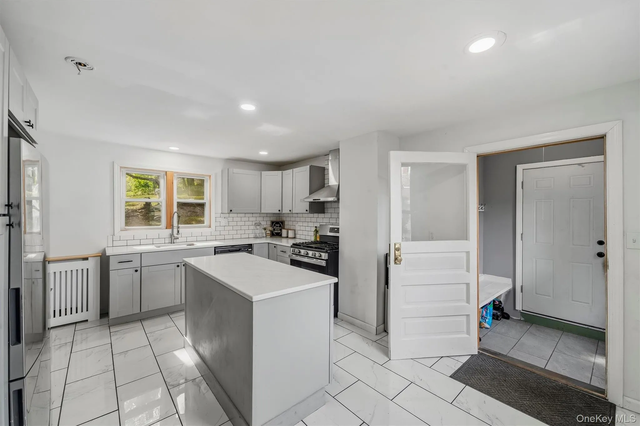 Kitchen featuring an island with a light-toned countertop, subway tile backsplash, stainless steel appliances, and recessed lighting Kitchen featuring an island with a light-toned countertop, subway tile backsplash, stainless steel appliances, and recessed lighting