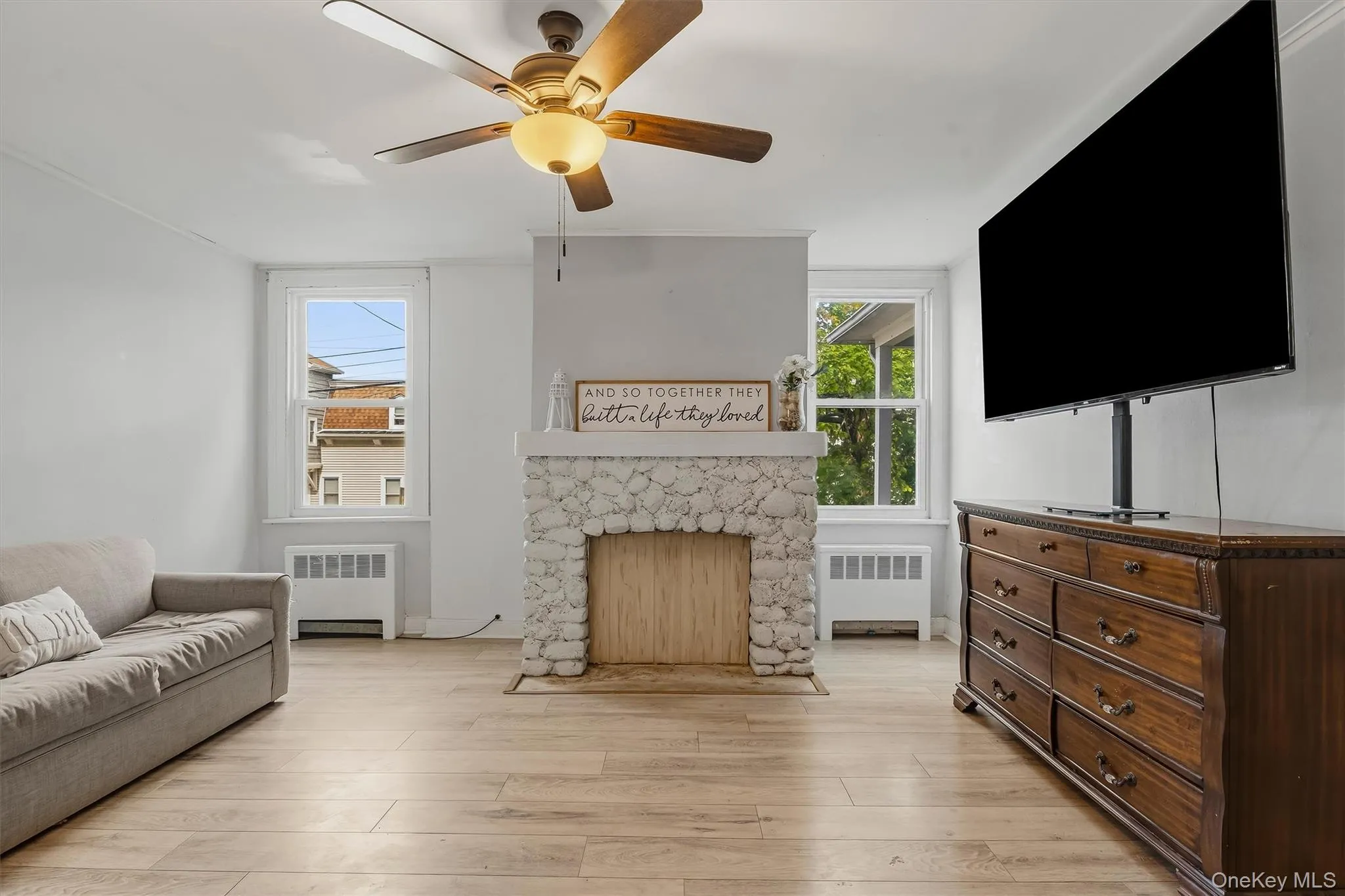 Light wood-finish flooring, a white stone-clad fireplace, and multiple windows Light wood-finish flooring, a white stone-clad fireplace, and multiple windows
