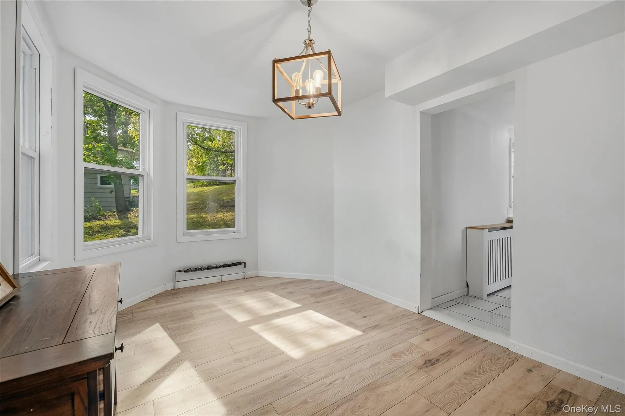 White walls, wood-finish flooring, and a contemporary chandelier White walls, wood-finish flooring, and a contemporary chandelier
