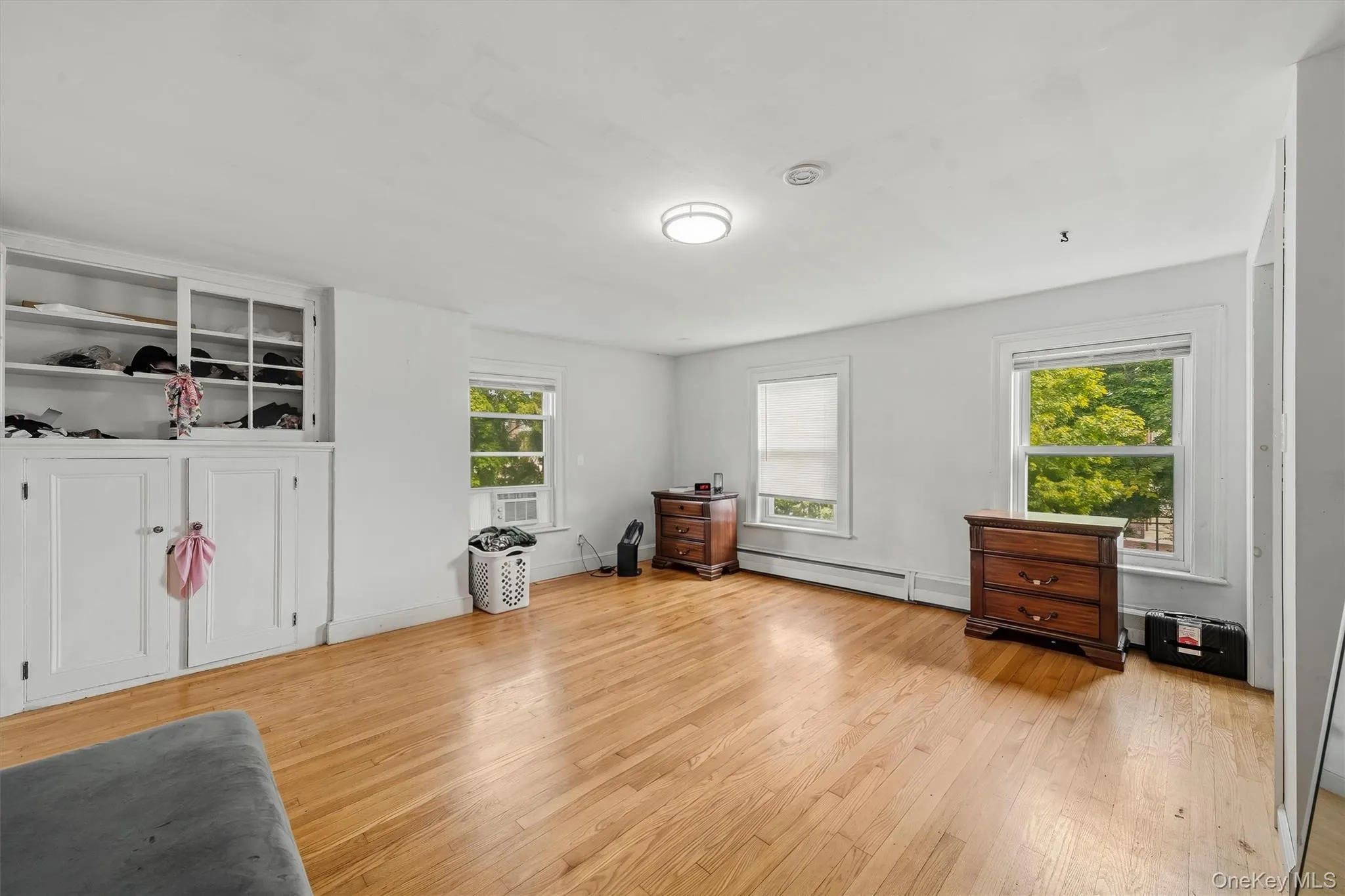 Large bedroom with hardwood floors, multiple windows, and built-in storage. Large bedroom with hardwood floors, multiple windows, and built-in storage.