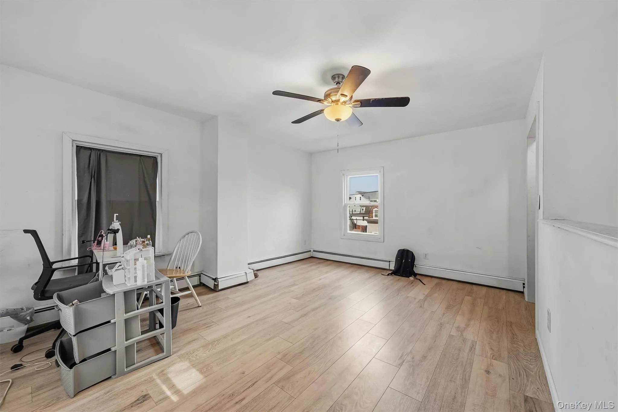 Light wood-finish flooring, white painted walls, and a ceiling fan with integrated lighting Light wood-finish flooring, white painted walls, and a ceiling fan with integrated lighting