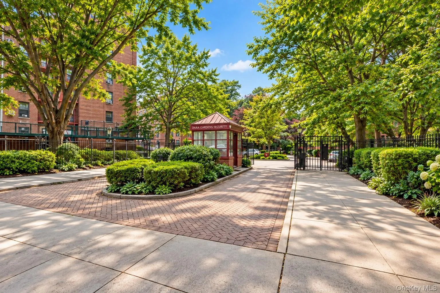 Brick paver driveway with integrated landscaping, wrought iron fencing, and mature trees Brick paver driveway with integrated landscaping, wrought iron fencing, and mature trees