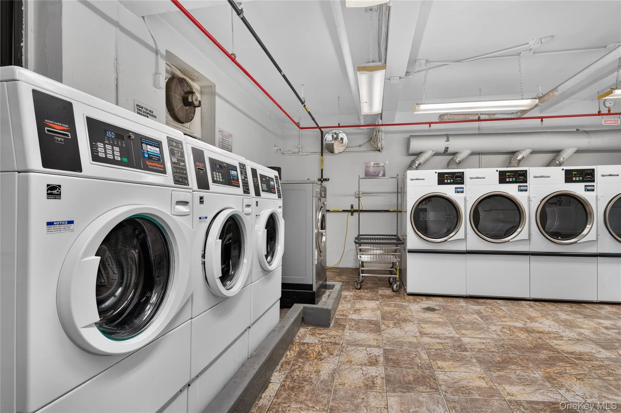 On-site laundry facility featuring multiple front-loading washers and dryers, finished with durable tile flooring On-site laundry facility featuring multiple front-loading washers and dryers, finished with durable tile flooring