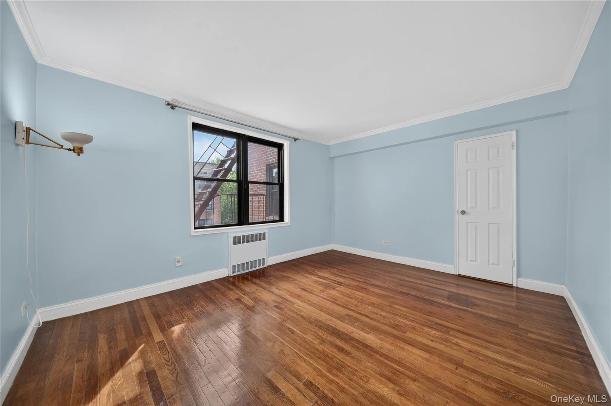 Hardwood flooring, crown molding, white trim, paneled door, and a built-in wall sconce Hardwood flooring, crown molding, white trim, paneled door, and a built-in wall sconce