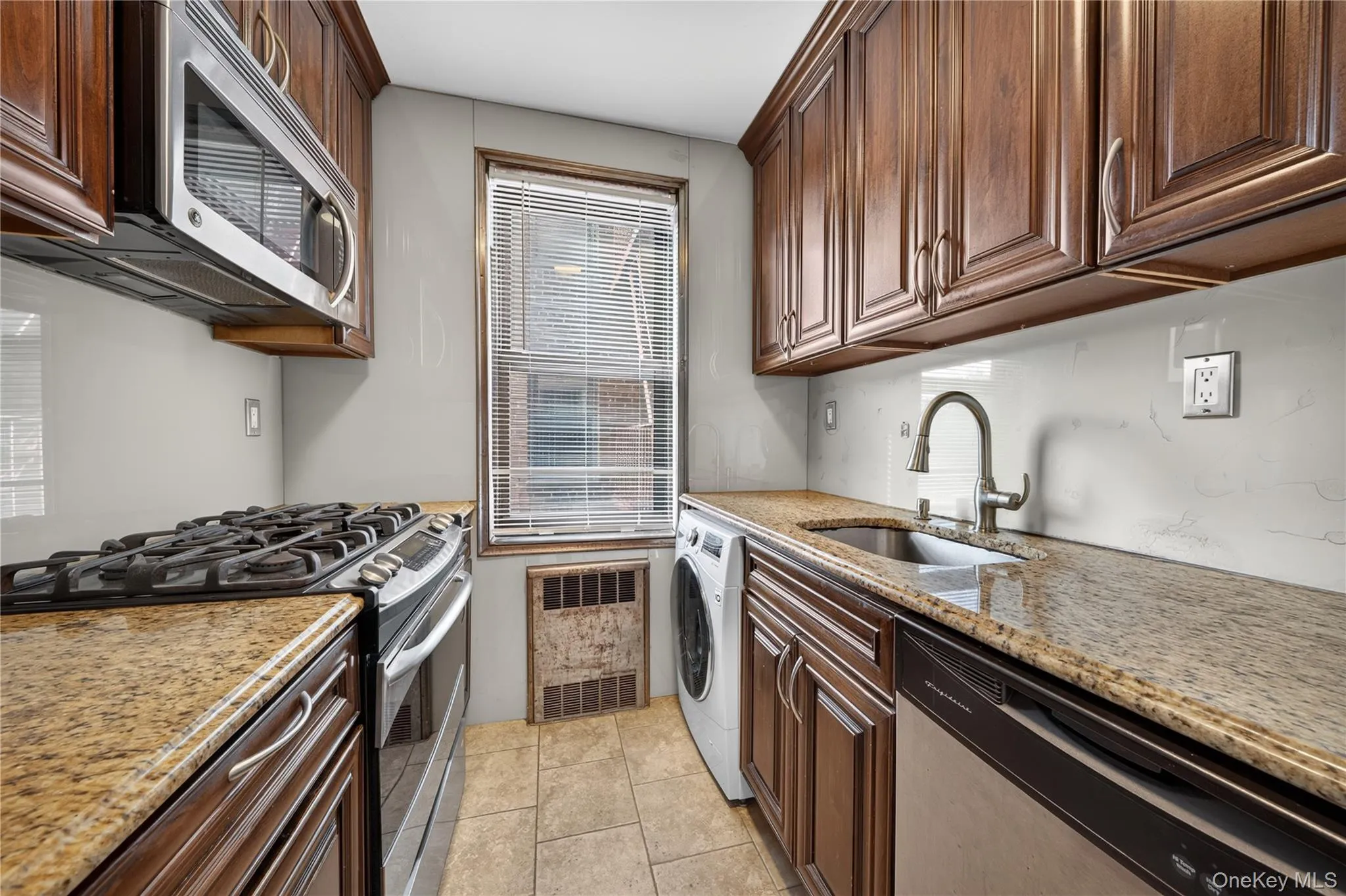 Wood-finish cabinetry, stainless steel appliances, granite-style countertops, and tiled flooring Wood-finish cabinetry, stainless steel appliances, granite-style countertops, and tiled flooring
