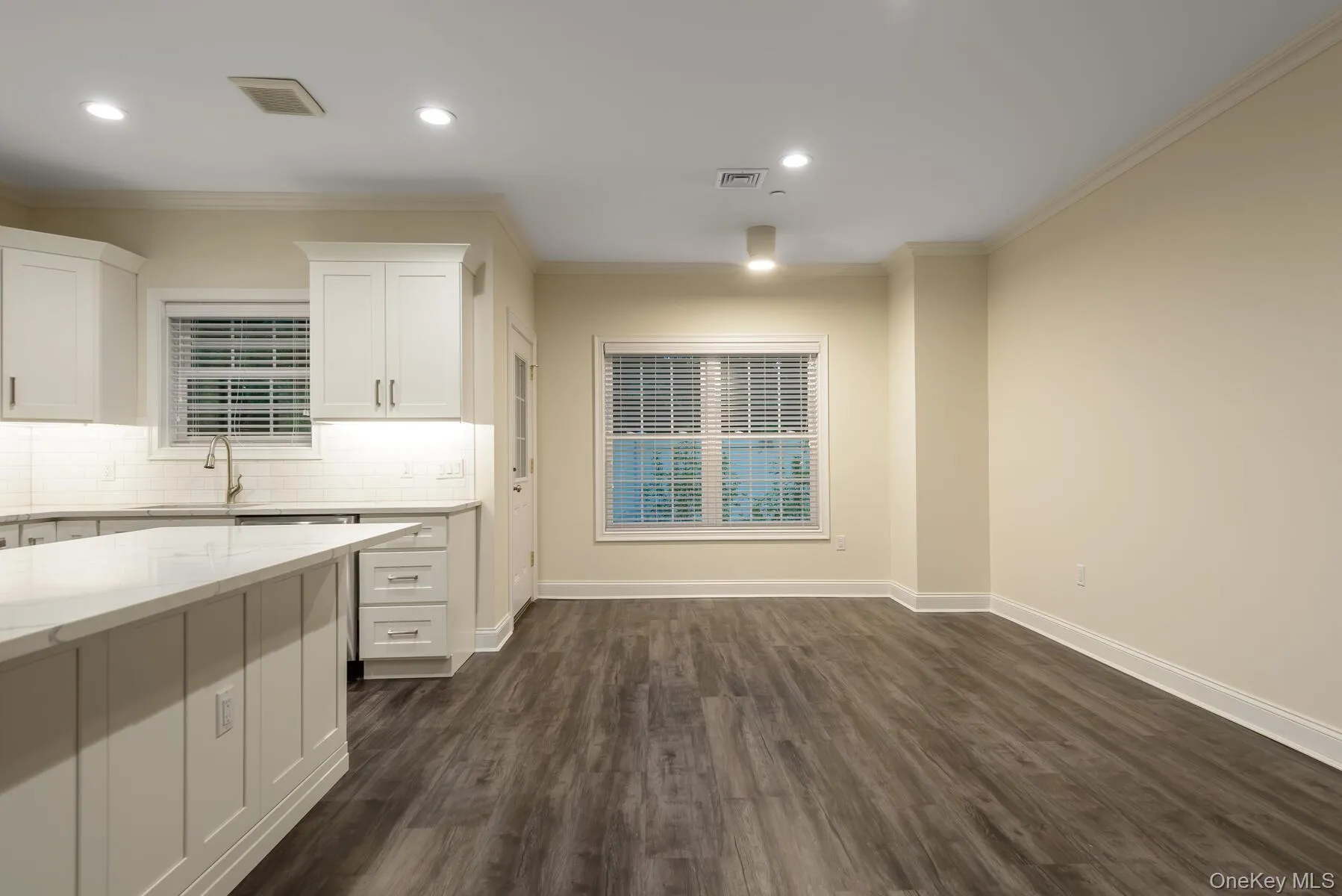 White cabinetry with under-cabinet lighting, stainless steel sink, and light-toned countertops White cabinetry with under-cabinet lighting, stainless steel sink, and light-toned countertops