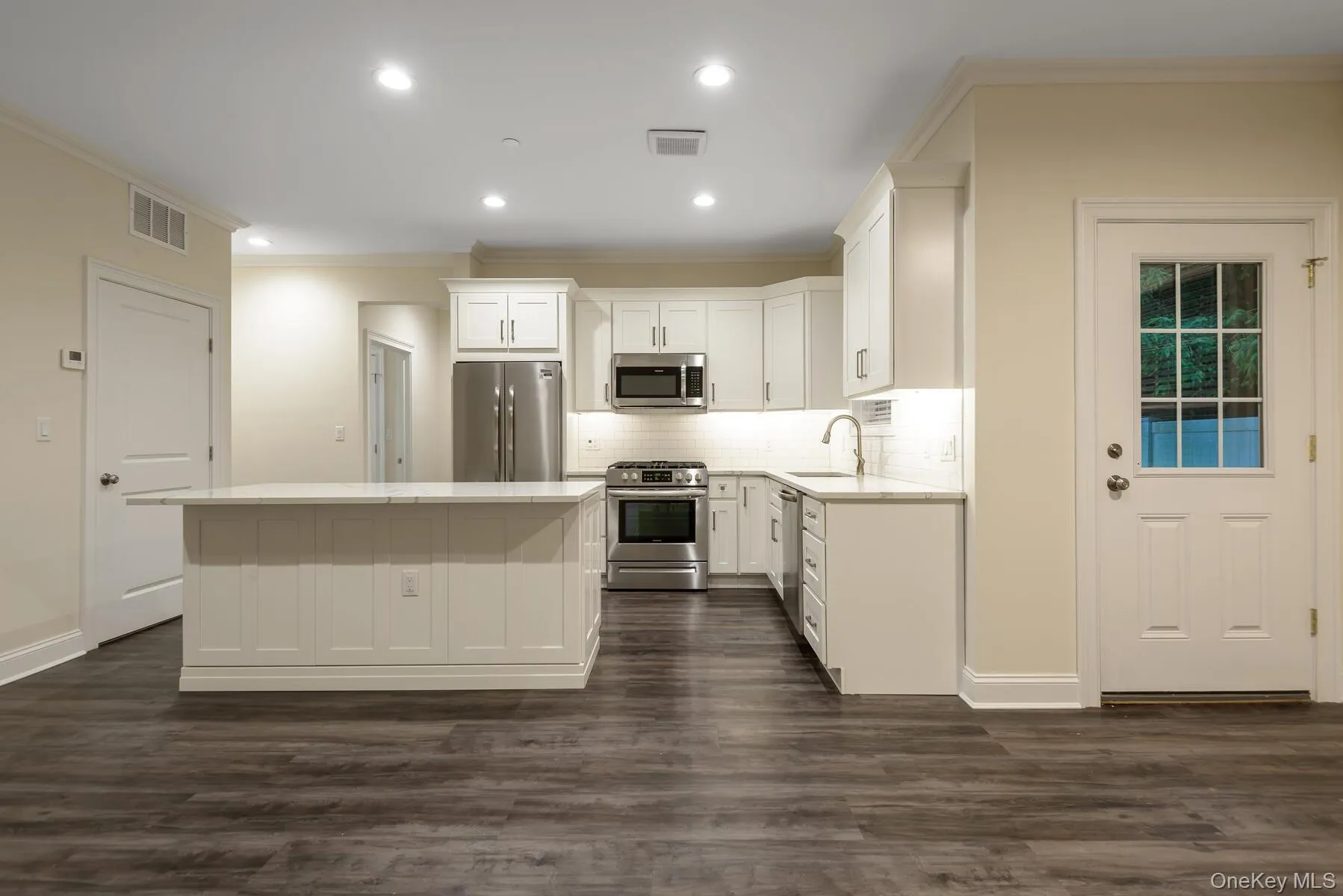 Kitchen featuring white cabinetry, stainless steel appliances, a center island with countertop seating, recessed lighting, and wood-finish flooring Kitchen featuring white cabinetry, stainless steel appliances, a center island with countertop seating, recessed lighting, and wood-finish flooring