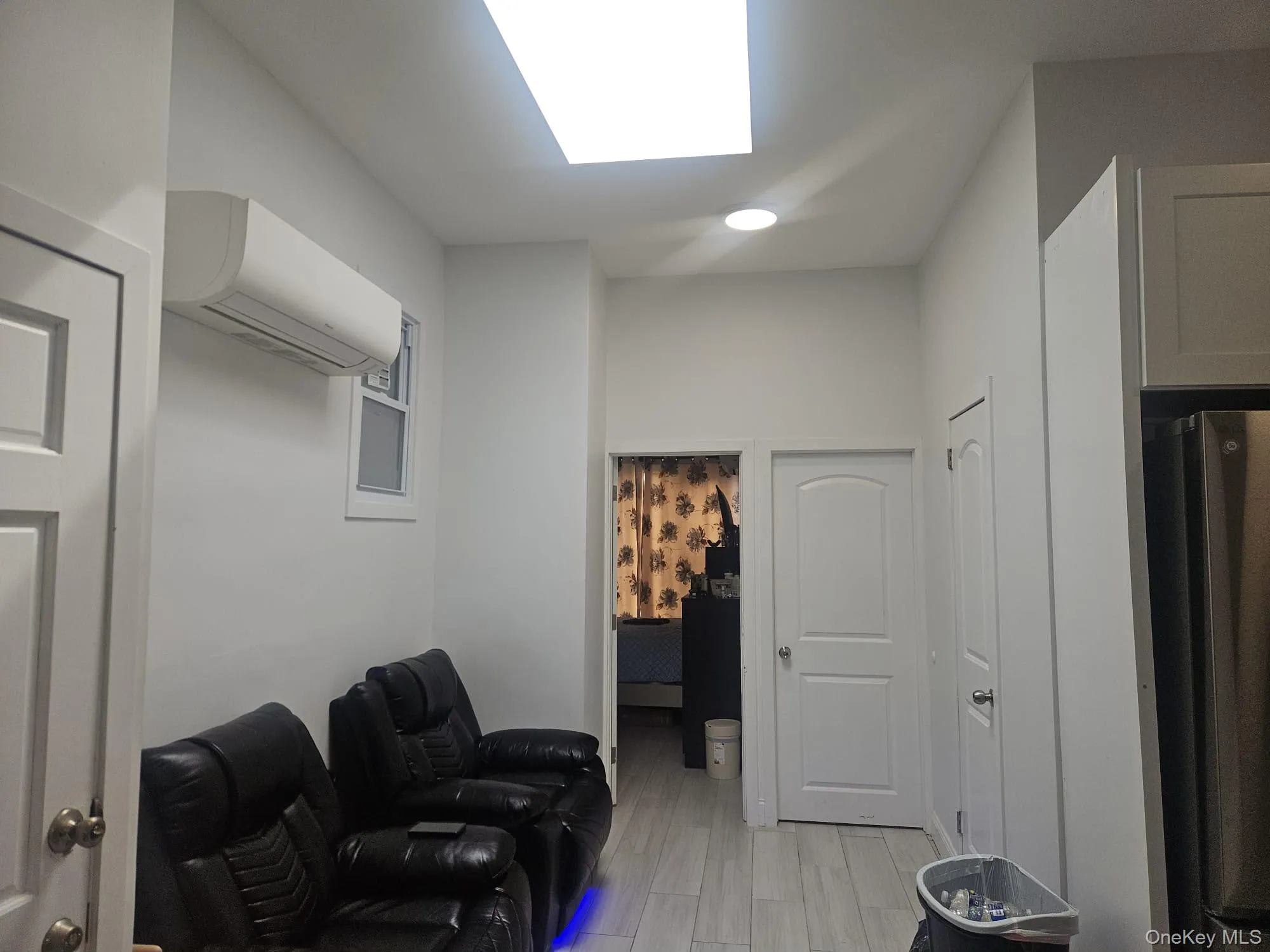 Recessed lighting, wood-finish flooring, white paneled doors, and a wall-mounted air conditioning unit Recessed lighting, wood-finish flooring, white paneled doors, and a wall-mounted air conditioning unit