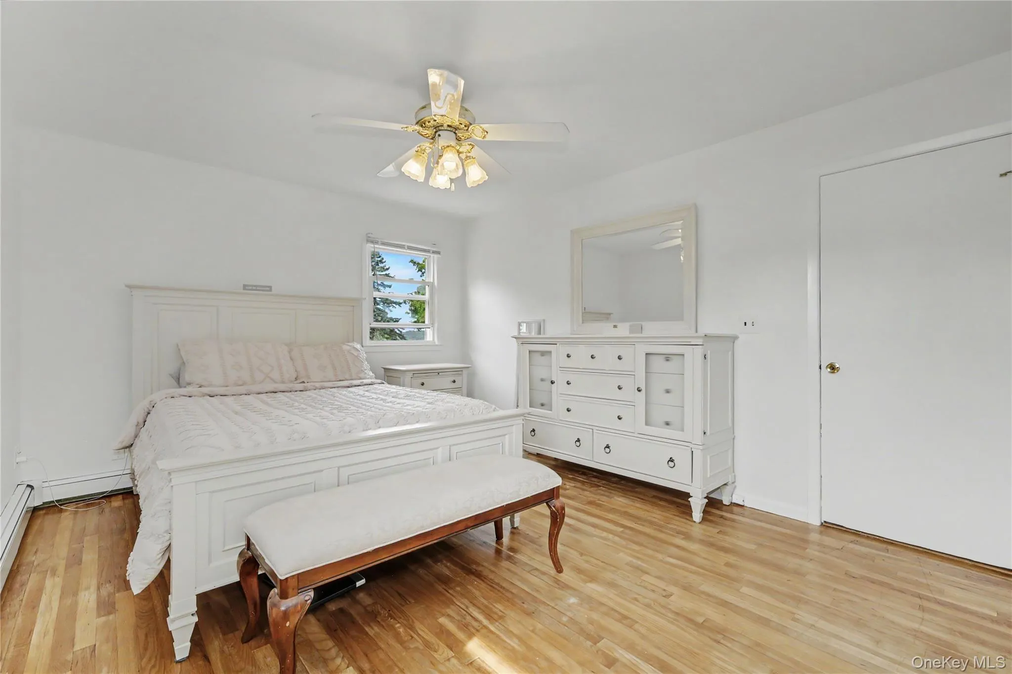 Substantially sized primary bedroom with warm oak flooring and ceiling fan Substantially sized primary bedroom with warm oak flooring and ceiling fan