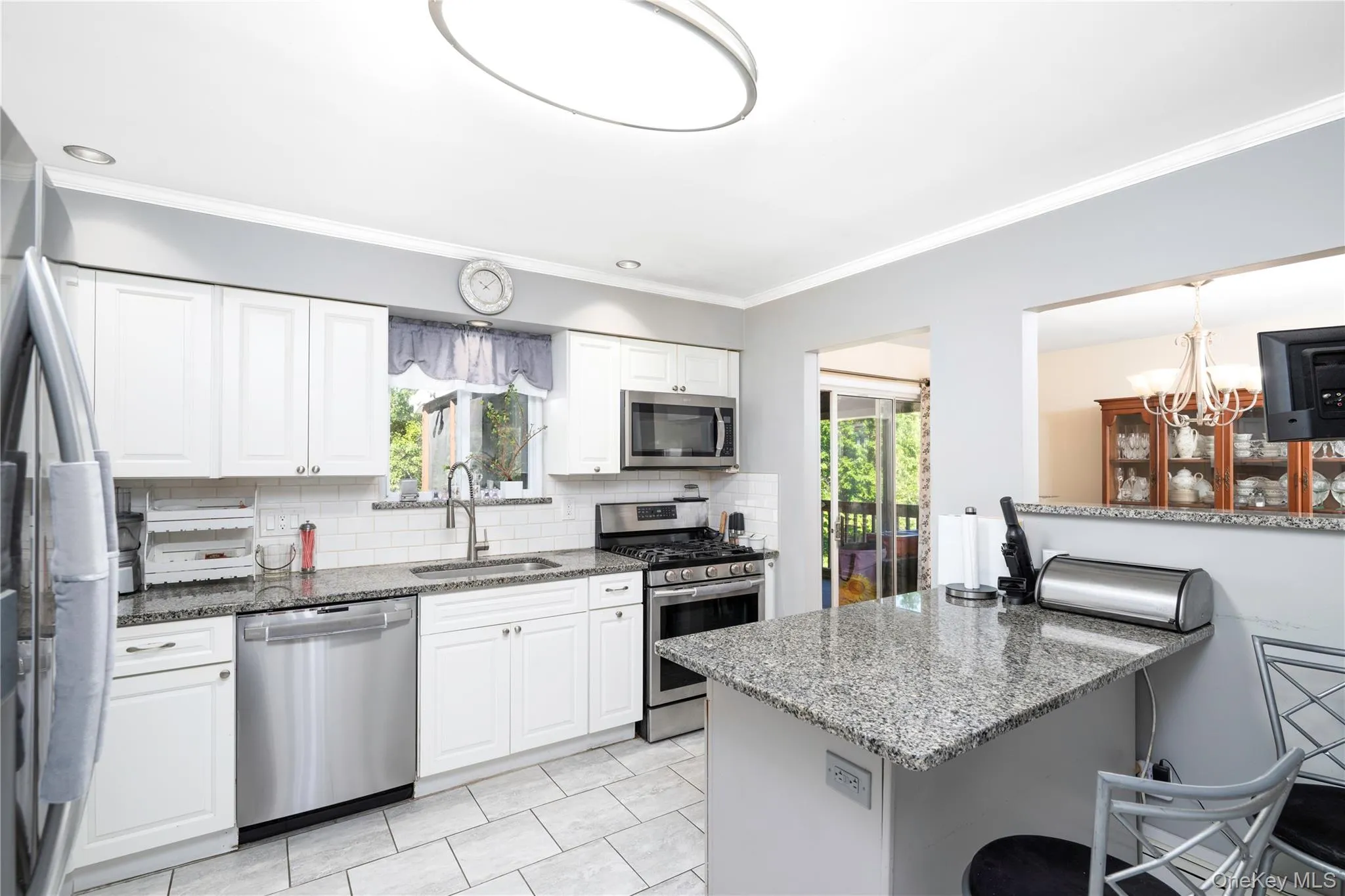 White shaker cabinetry, stainless steel appliances, granite countertops, subway tile backsplash, and tile flooring White shaker cabinetry, stainless steel appliances, granite countertops, subway tile backsplash, and tile flooring