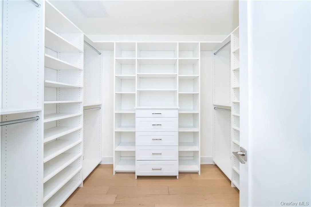 Spacious closet with light hardwood / wood-style flooring Spacious closet with light hardwood / wood-style flooring