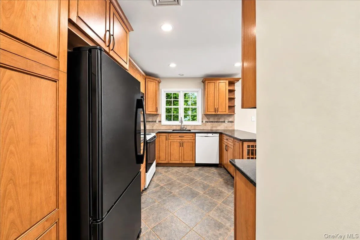 Updated kitchen featuring warm wood cabinetry, a ceramic tile backsplash, and ceramic tile flooring, with beautiful Hudson River views from the window above the sink. Updated kitchen featuring warm wood cabinetry, a ceramic tile backsplash, and ceramic tile flooring, with beautiful Hudson River views from the window above the sink.