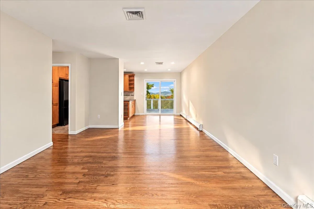 Bright living room with newly refinished hardwood floors flowing seamlessly into the dining room and kitchen, offering beautiful river views. Bright living room with newly refinished hardwood floors flowing seamlessly into the dining room and kitchen, offering beautiful river views.