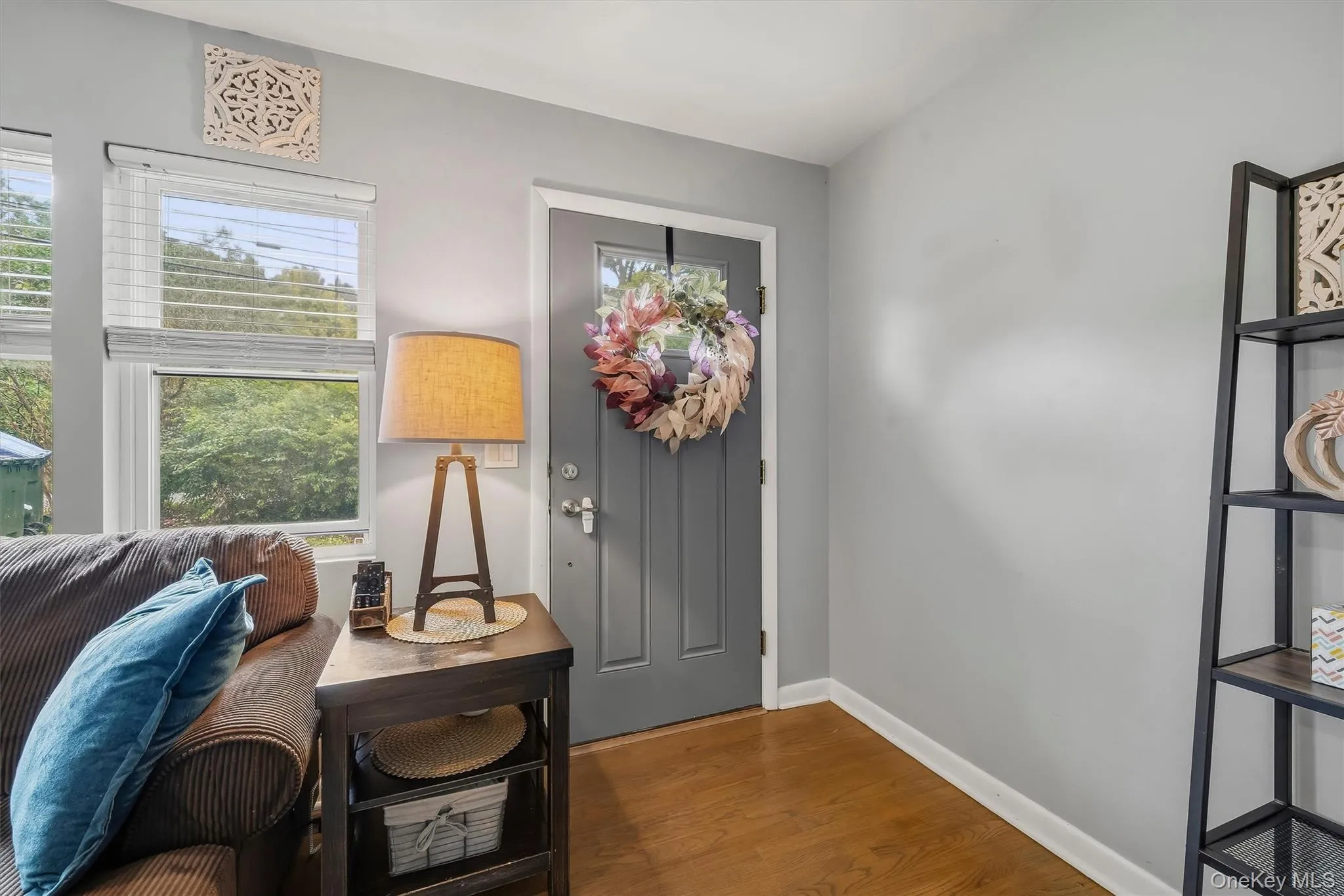Hardwood-finish flooring, light gray wall finishes, and a paneled entry door with glass insert Hardwood-finish flooring, light gray wall finishes, and a paneled entry door with glass insert