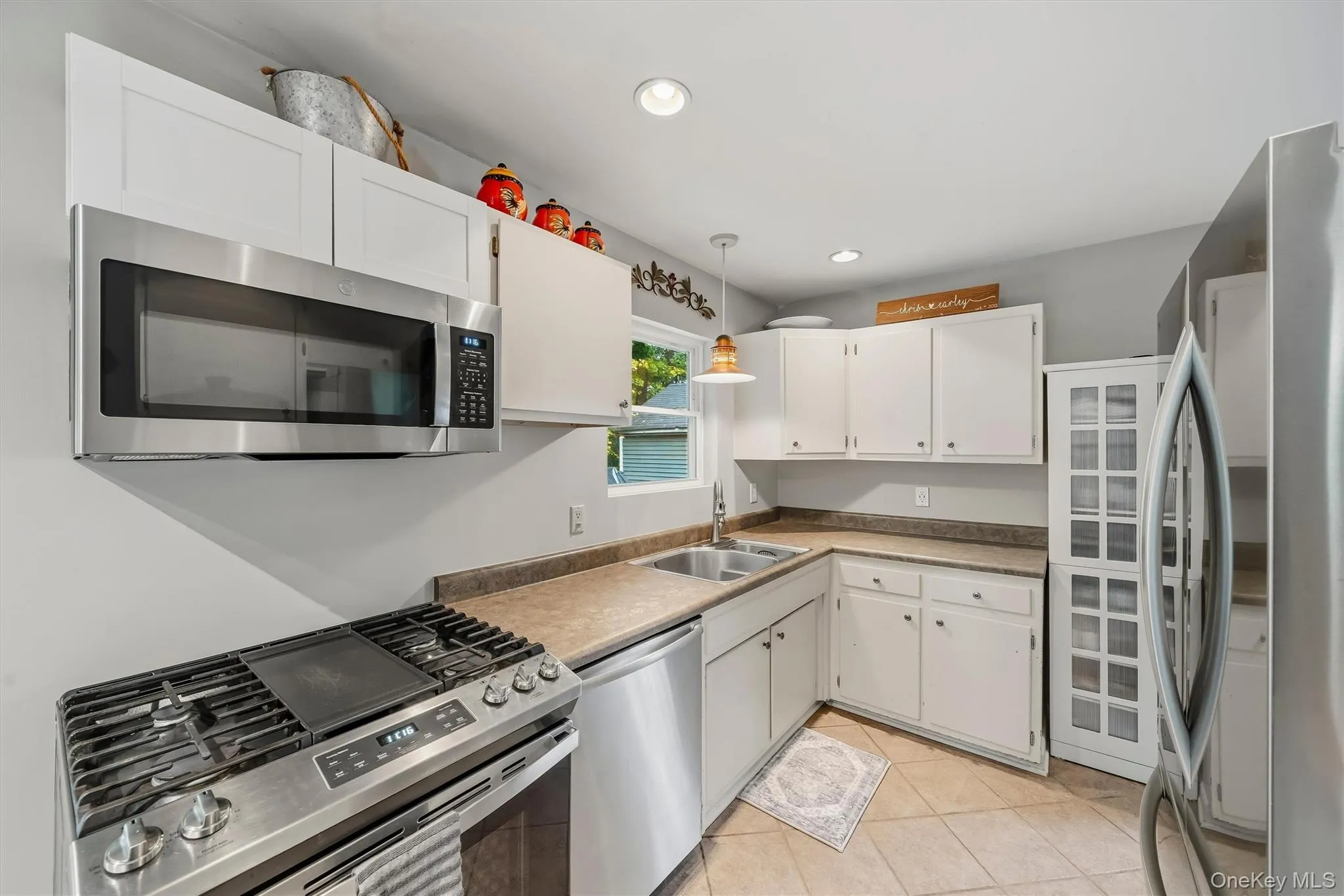Kitchen with white cabinetry, stainless steel appliances, dual basin sink, and tile flooring Kitchen with white cabinetry, stainless steel appliances, dual basin sink, and tile flooring