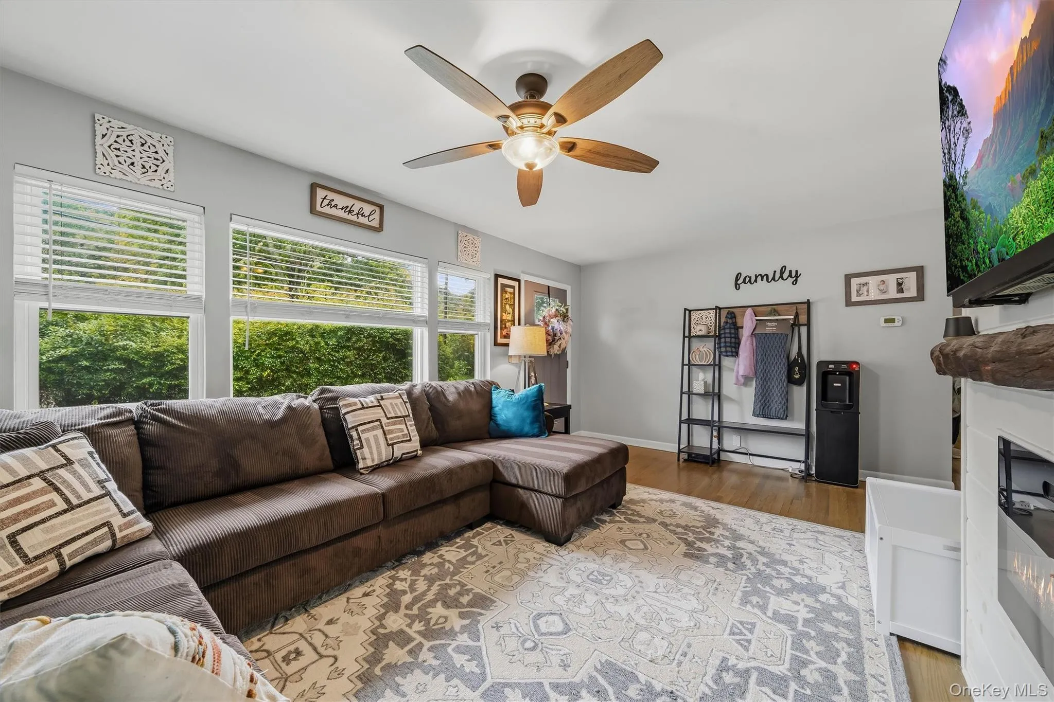 Wood-finish flooring, multiple windows with blinds, and a ceiling fan with light Wood-finish flooring, multiple windows with blinds, and a ceiling fan with light