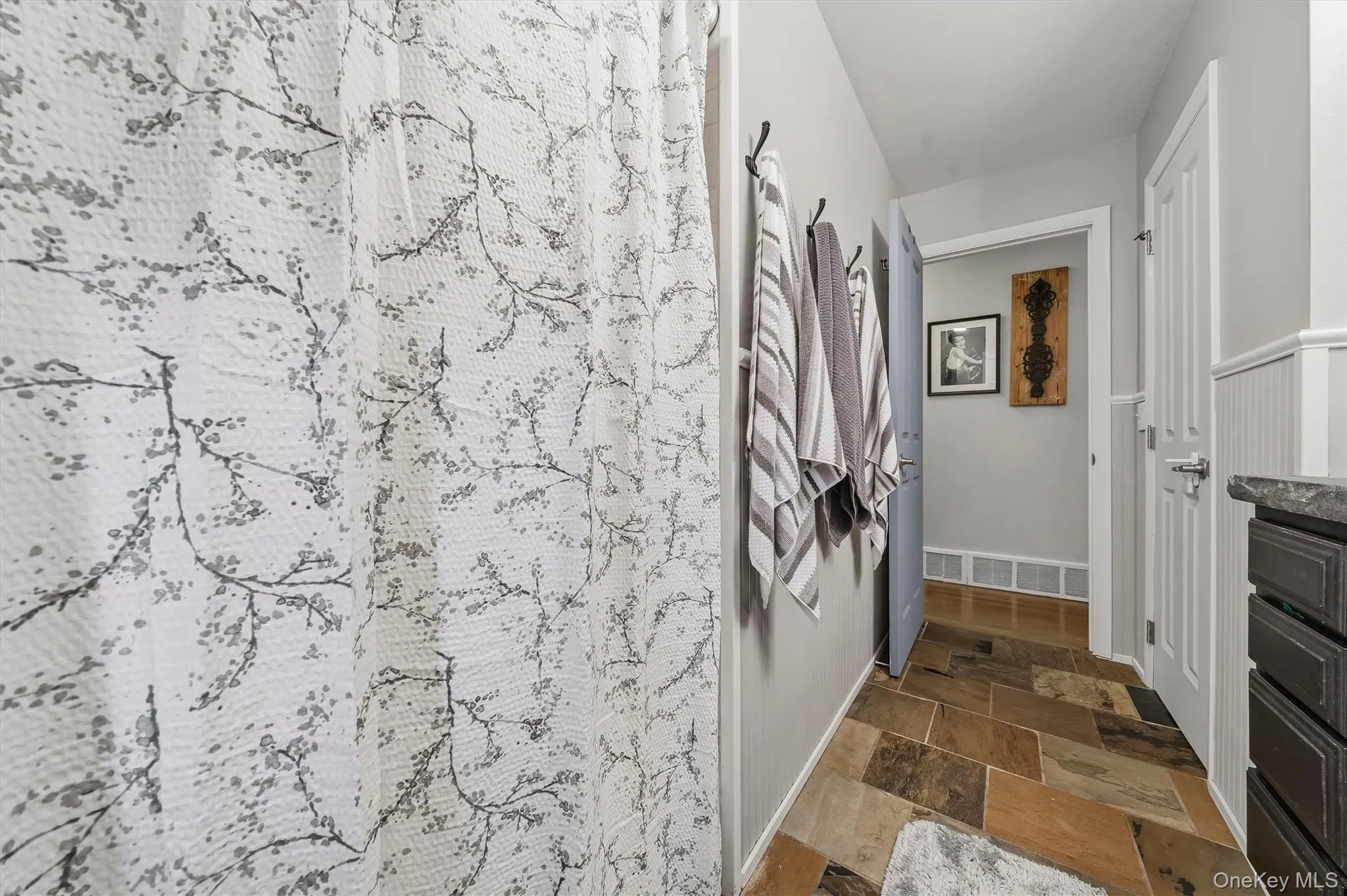 Multi-toned tile flooring, white wainscoting, dark wood-finish cabinetry, and a dark countertop Multi-toned tile flooring, white wainscoting, dark wood-finish cabinetry, and a dark countertop