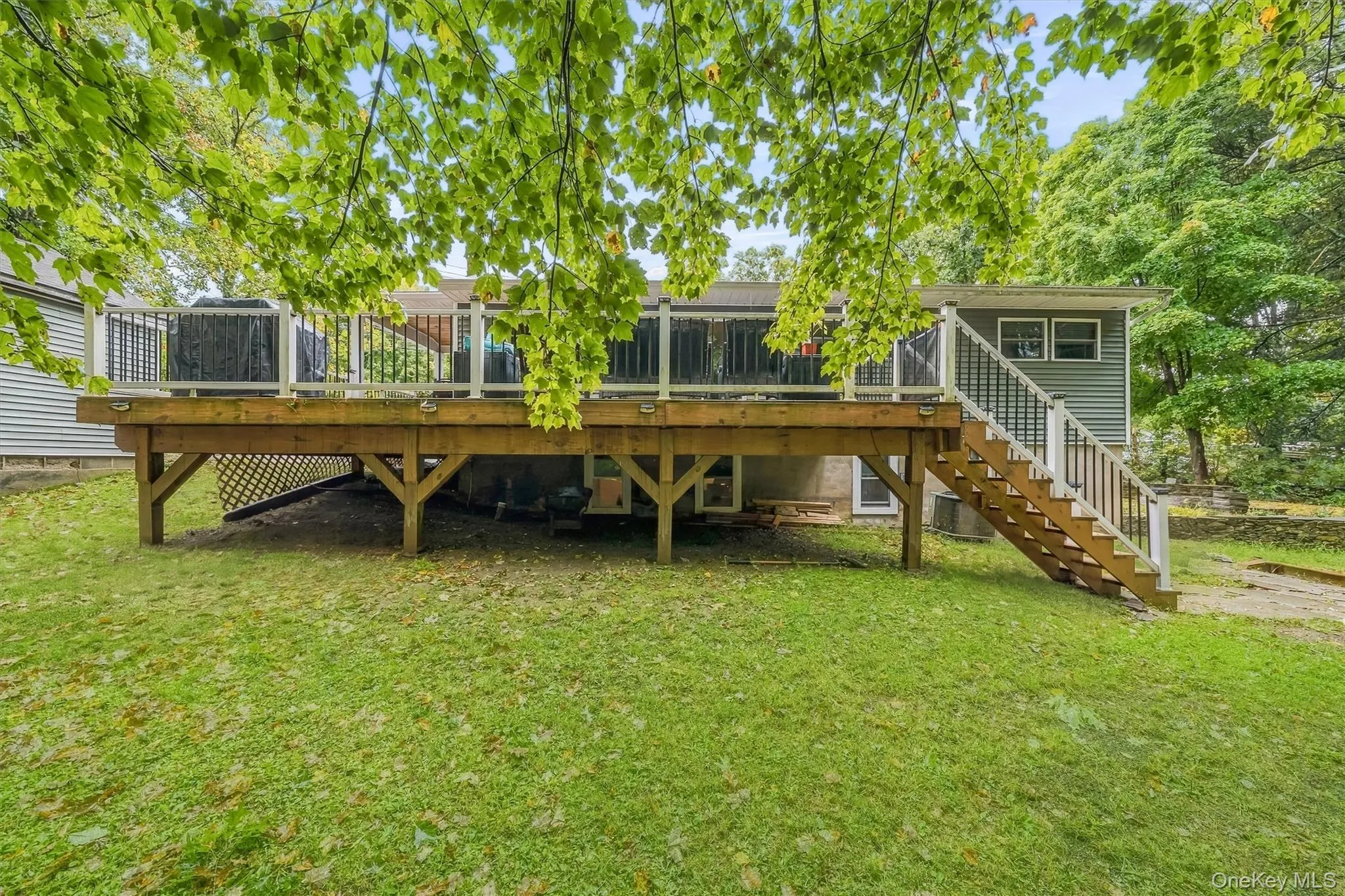 Expansive wood deck with white and black railings, lattice skirting, and a staircase leading to the yard Expansive wood deck with white and black railings, lattice skirting, and a staircase leading to the yard