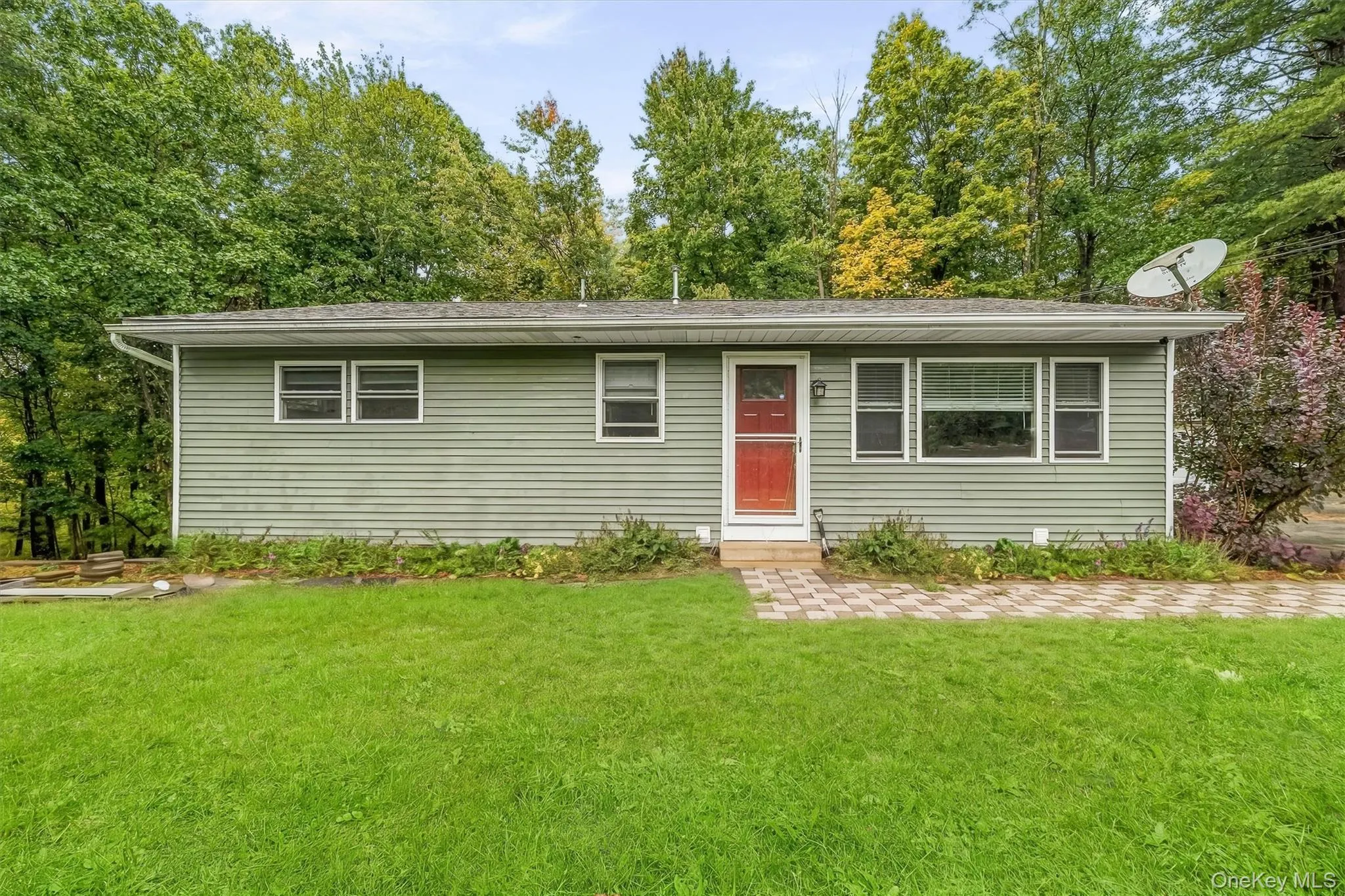 Single-story residence featuring light green horizontal siding and a red entry door Single-story residence featuring light green horizontal siding and a red entry door