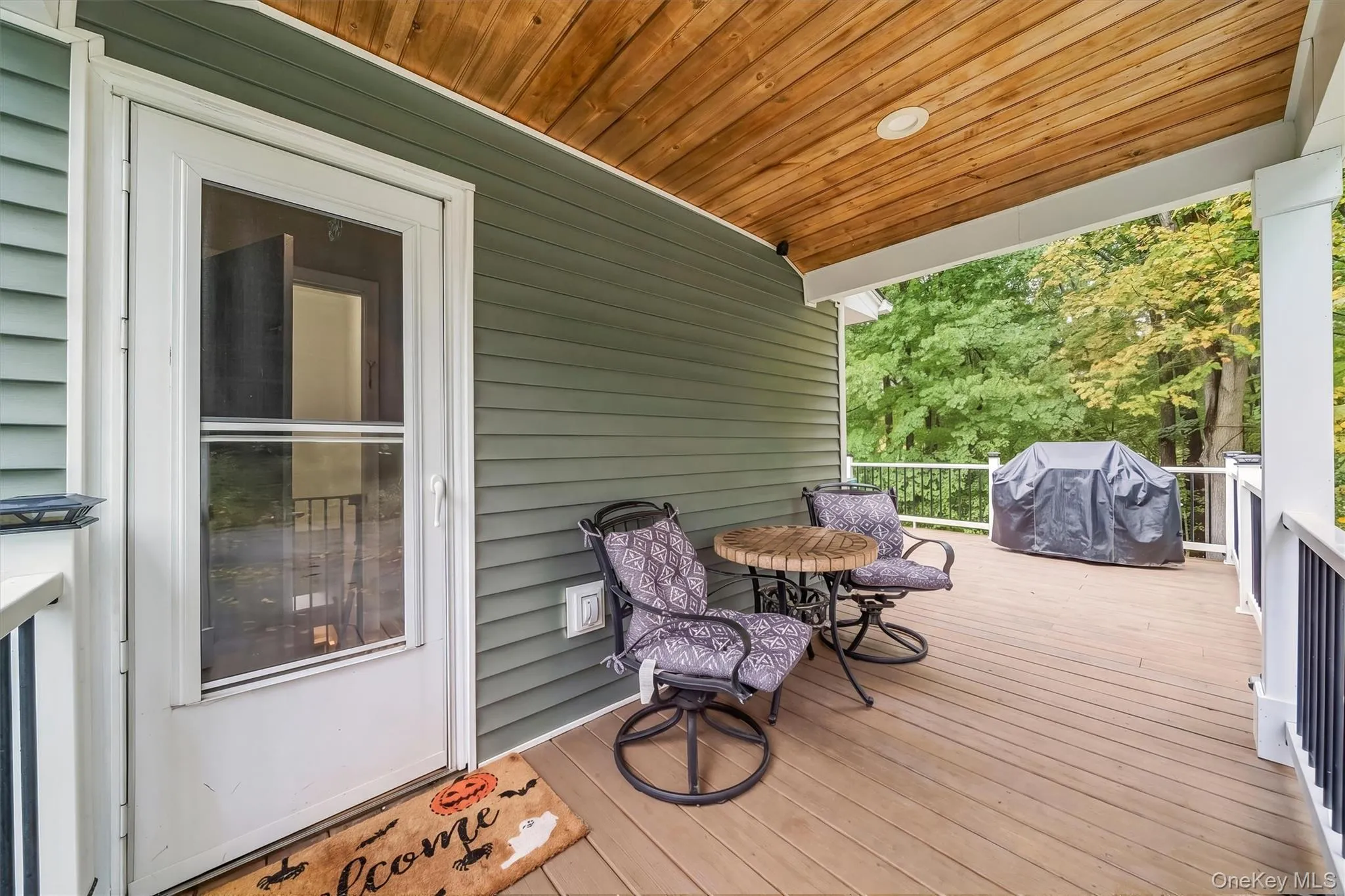 Covered patio with a wood-finish ceiling, composite decking, and white railing Covered patio with a wood-finish ceiling, composite decking, and white railing