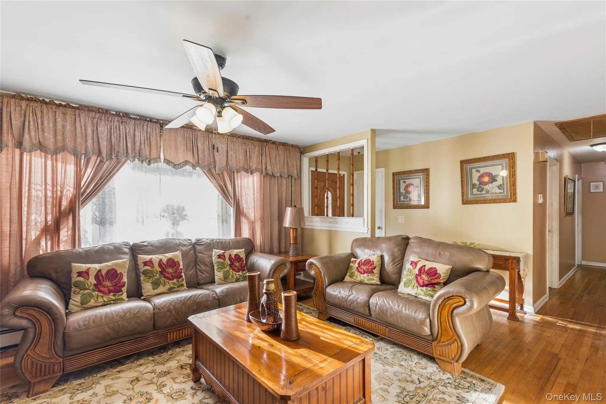 Hardwood flooring throughout, a ceiling fan with integrated lighting, and a large bay window Hardwood flooring throughout, a ceiling fan with integrated lighting, and a large bay window