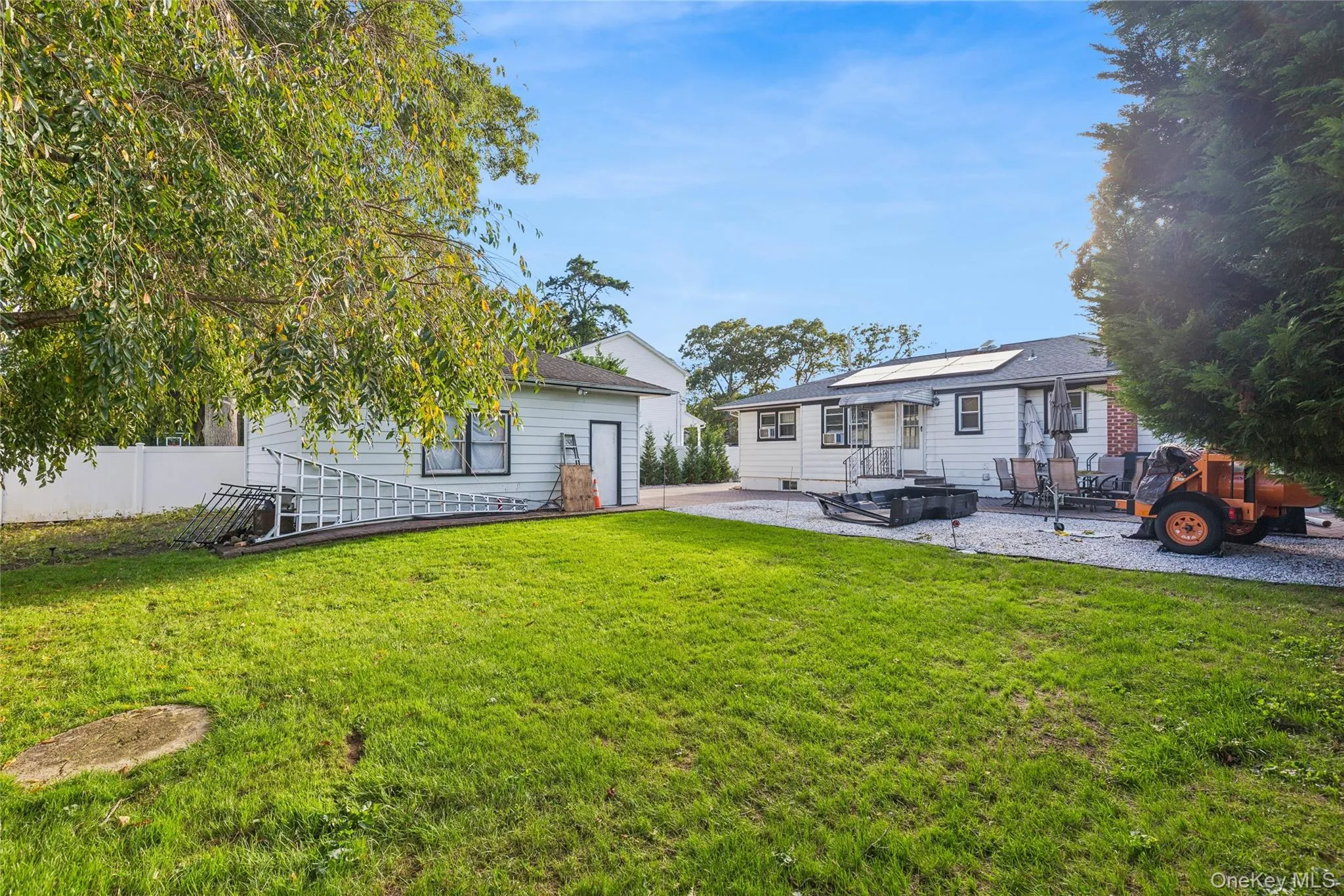 Expansive lawn area with a gravel patio, leading to a 2 car garage Expansive lawn area with a gravel patio, leading to a 2 car garage