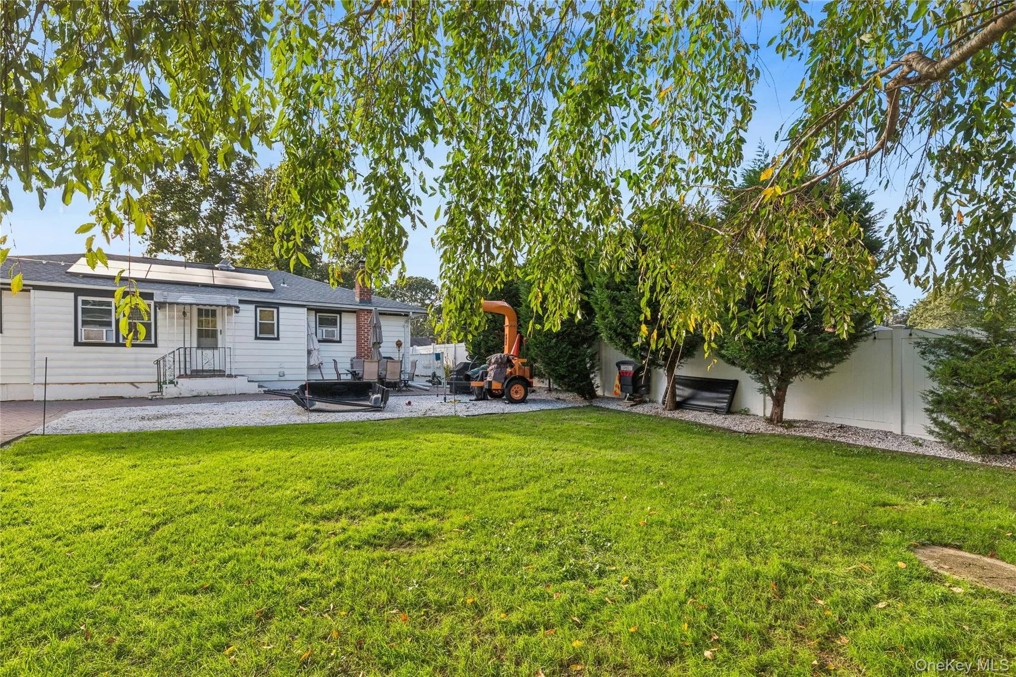 Expansive grass lawn with mature trees and a white privacy fence Expansive grass lawn with mature trees and a white privacy fence