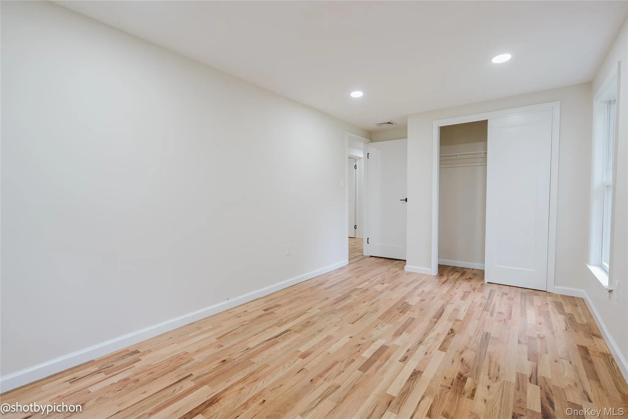 Hardwood flooring, recessed lighting, white walls, and a built-in closet Hardwood flooring, recessed lighting, white walls, and a built-in closet