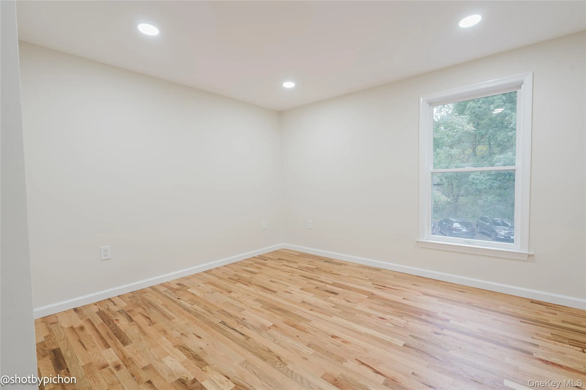 Hardwood flooring throughout, recessed ceiling lighting, and a white-trimmed window Hardwood flooring throughout, recessed ceiling lighting, and a white-trimmed window