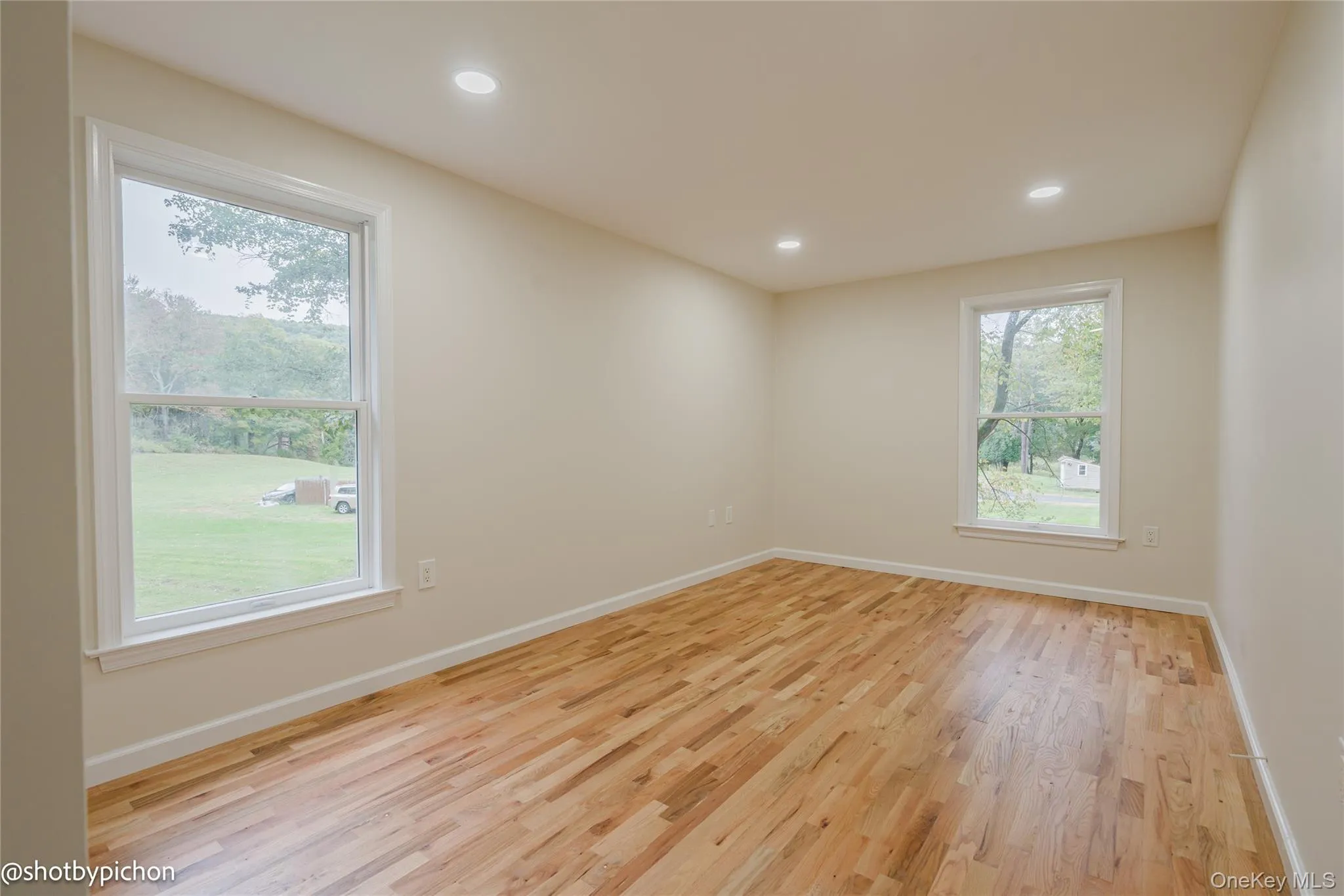Recessed ceiling lighting, wood-finish flooring, and multiple windows with white trim Recessed ceiling lighting, wood-finish flooring, and multiple windows with white trim