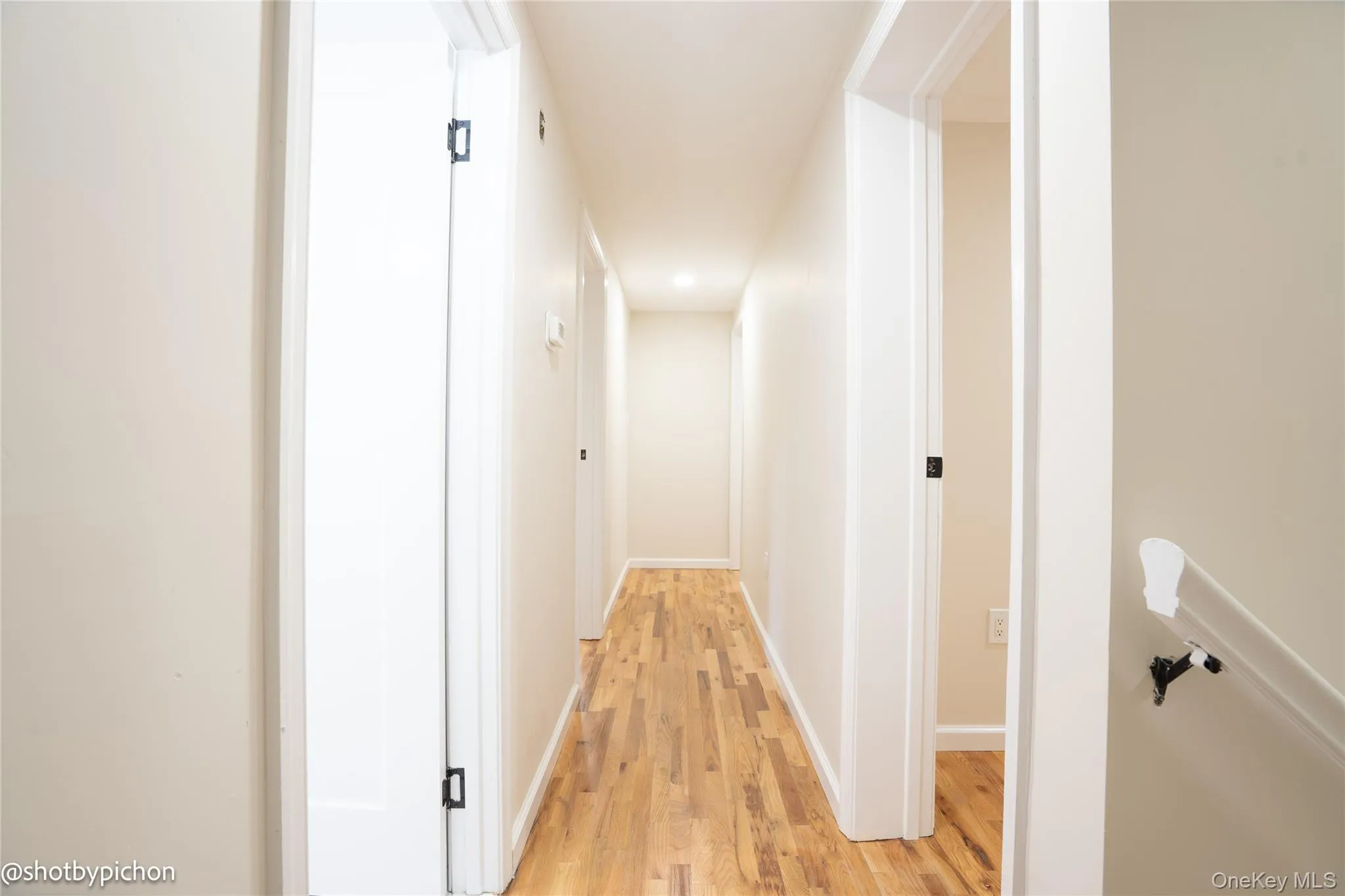 Hallway with wood-finish flooring, light-toned walls, and recessed lighting Hallway with wood-finish flooring, light-toned walls, and recessed lighting