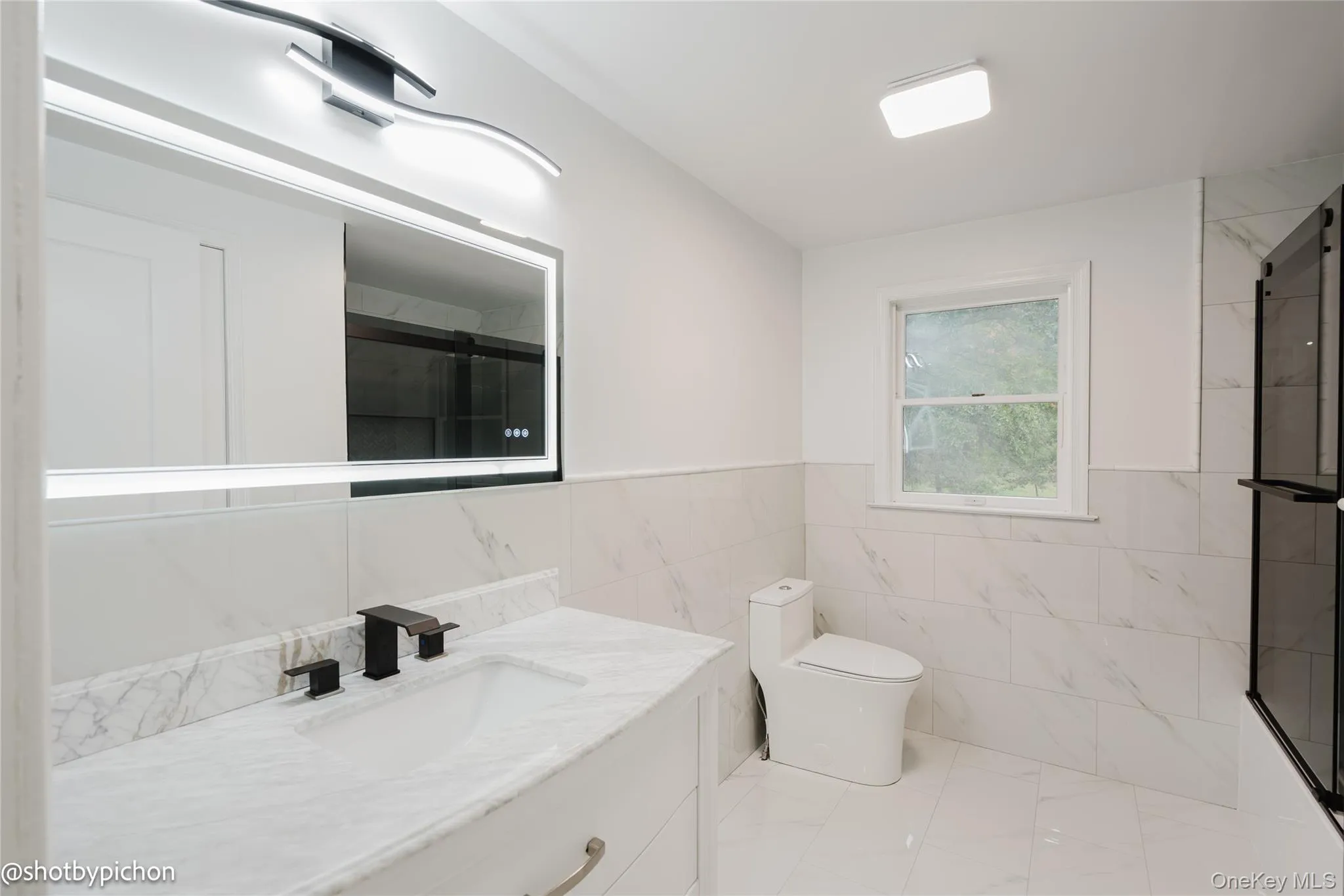 Vanity with a marble-finish countertop, integrated sink, and matte black faucet Vanity with a marble-finish countertop, integrated sink, and matte black faucet