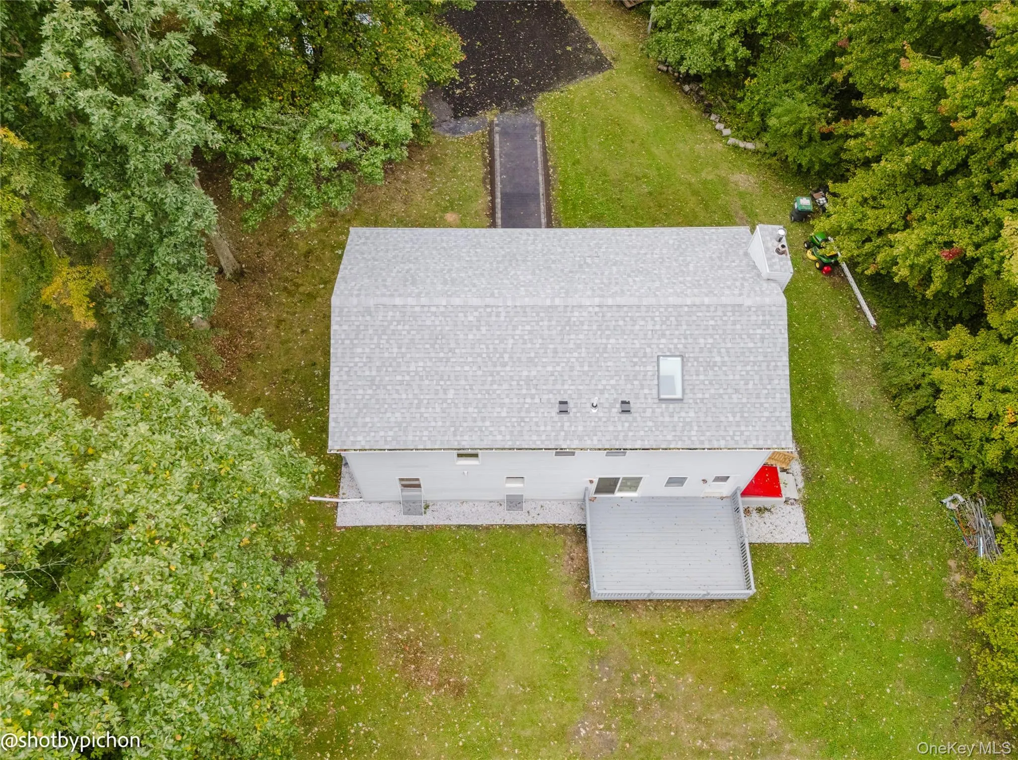 Gable roof with asphalt shingles and skylight, elevated deck, and flat backyard Gable roof with asphalt shingles and skylight, elevated deck, and flat backyard