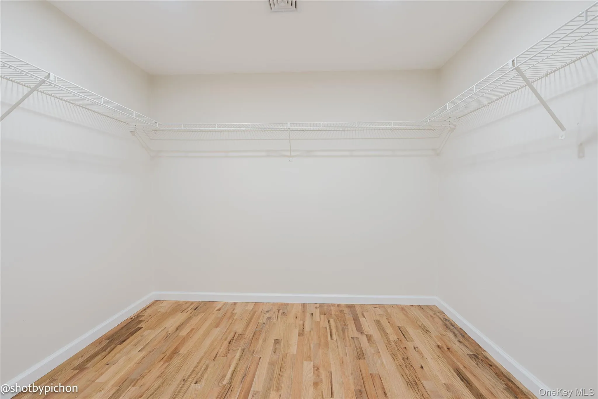 Large walk-in closet with wire shelving and wood-finish flooring Large walk-in closet with wire shelving and wood-finish flooring