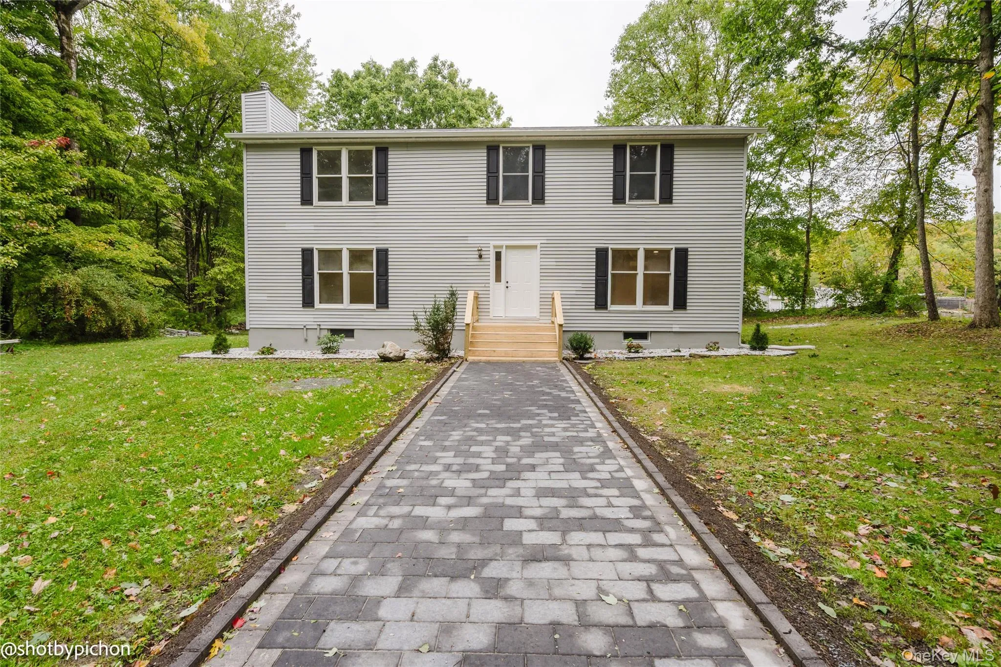 Two-story residence with light gray siding and black window shutters Two-story residence with light gray siding and black window shutters