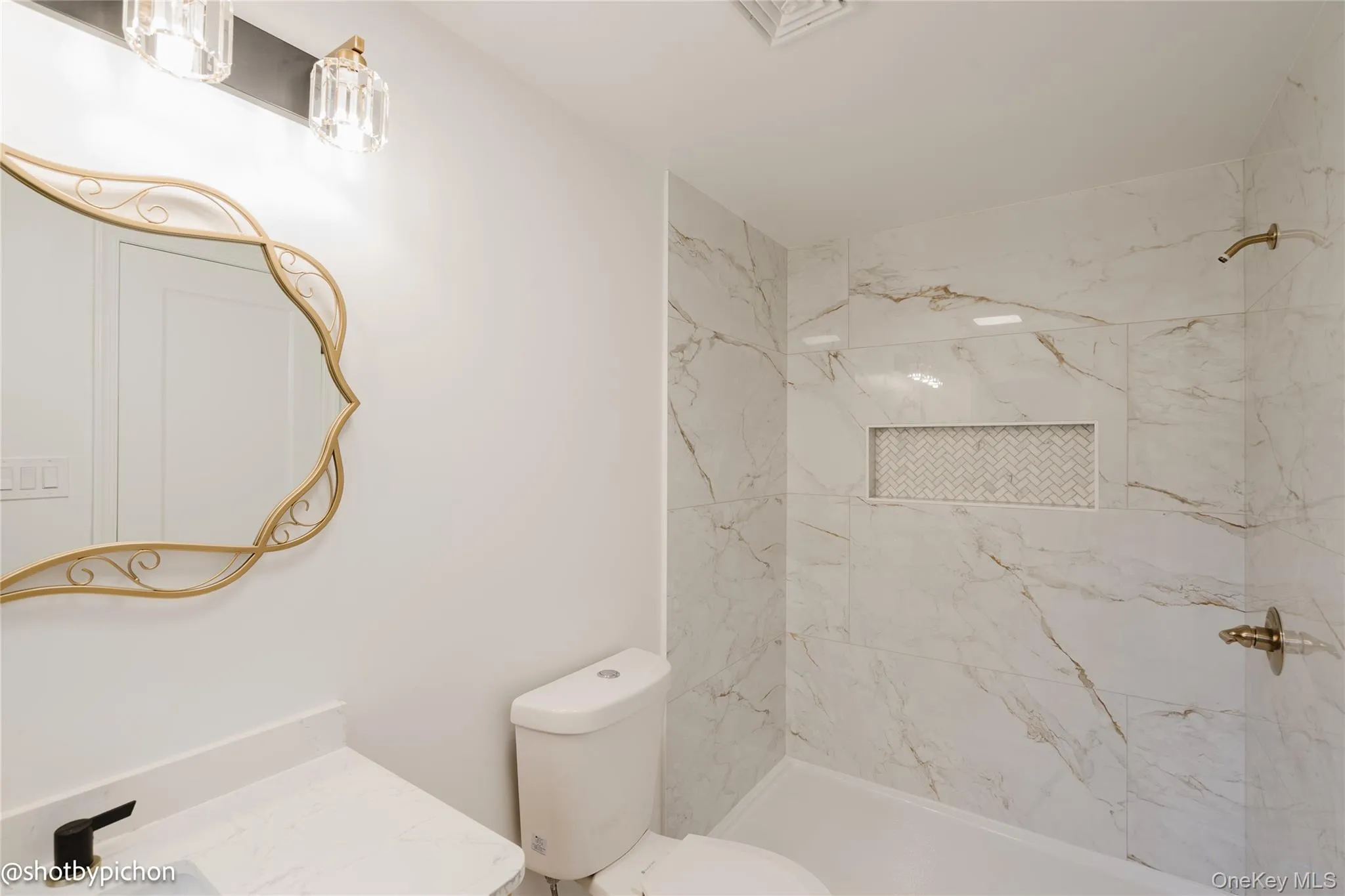 White vanity with a solid surface countertop, matte black faucet, and a decorative framed mirror White vanity with a solid surface countertop, matte black faucet, and a decorative framed mirror