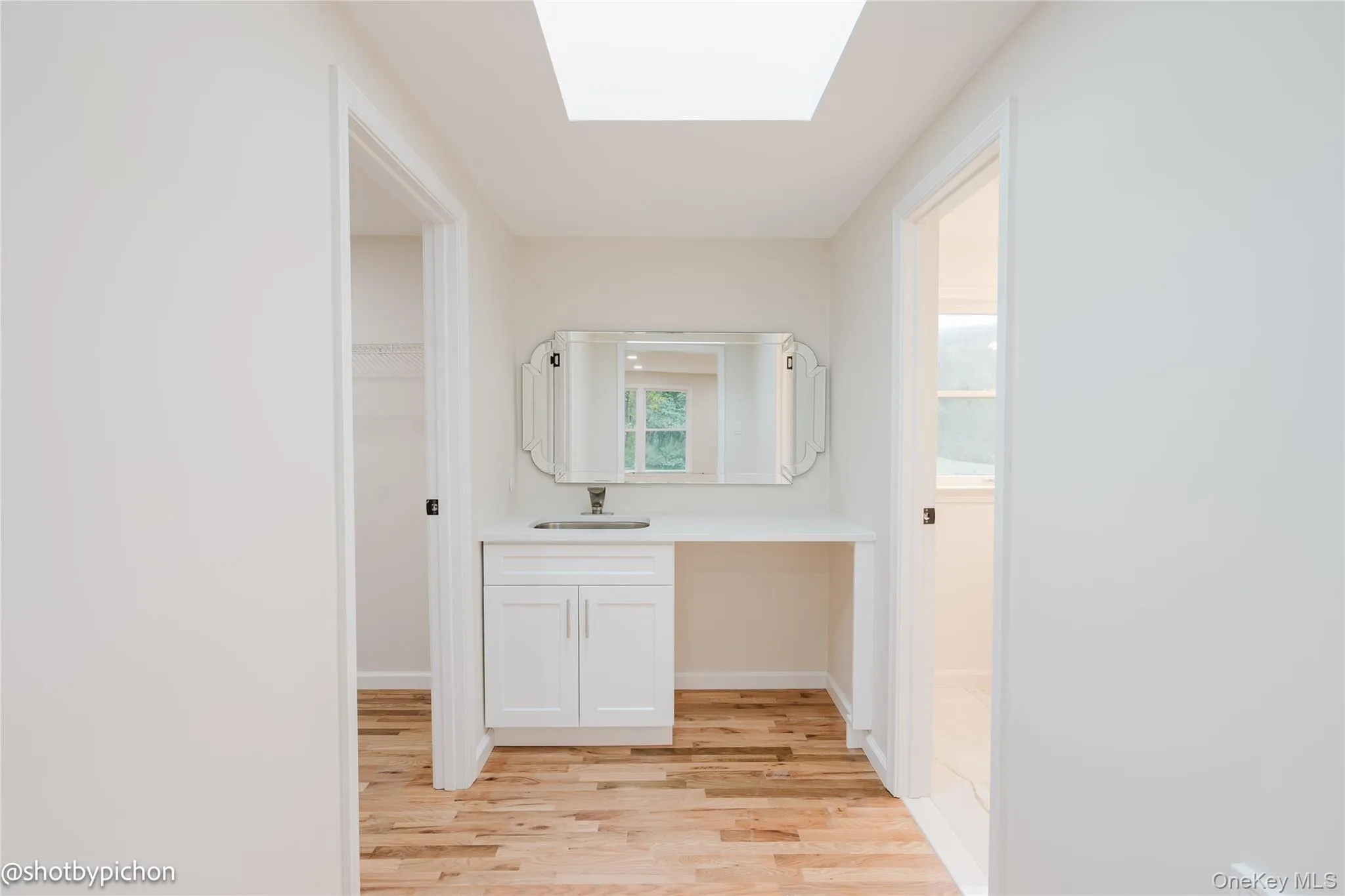 Wood-finish flooring, white walls, and a skylight provide a bright hallway Wood-finish flooring, white walls, and a skylight provide a bright hallway
