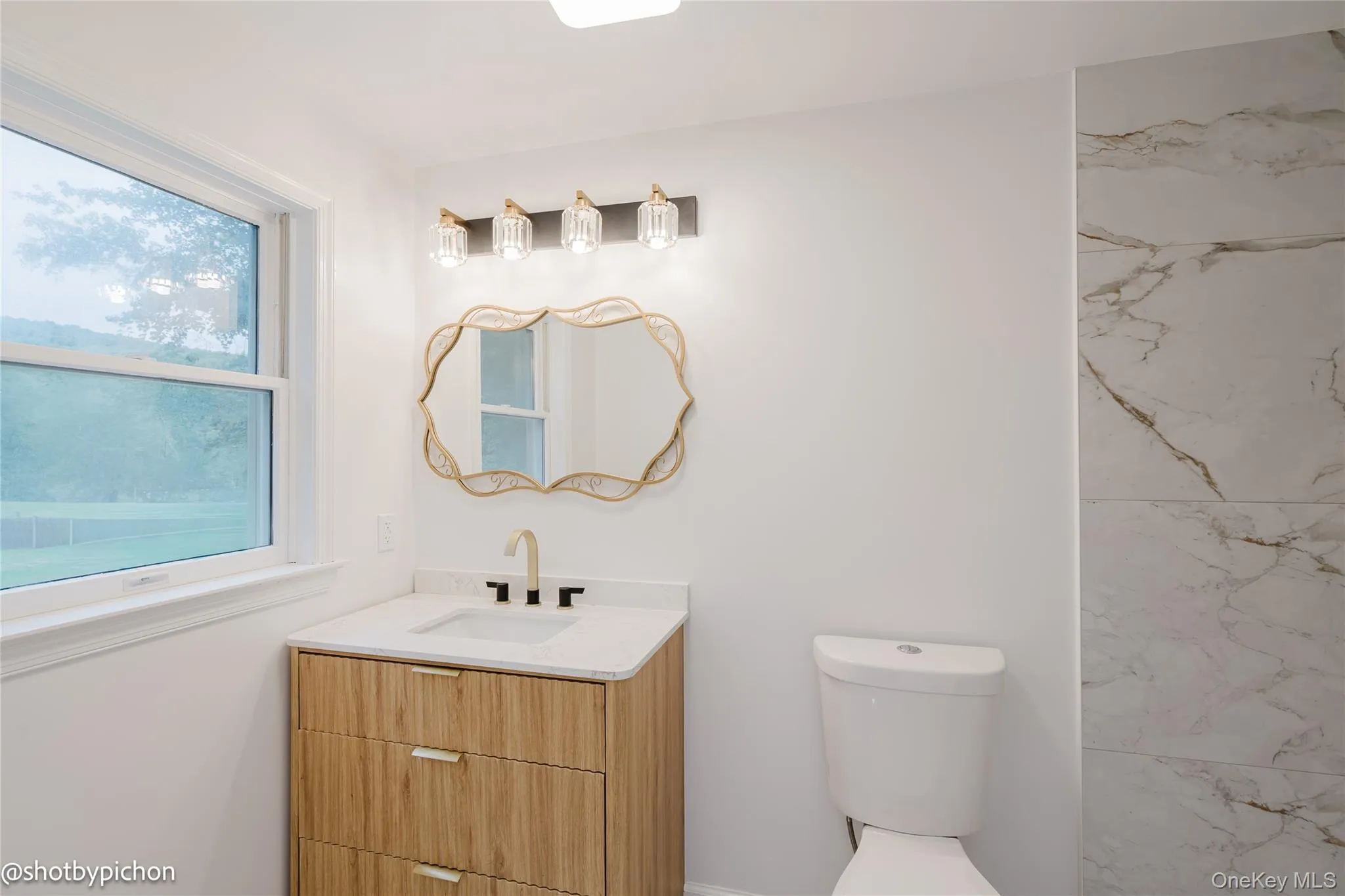 Wood-finish vanity with an integrated sink, quartz-style countertop, and a brushed gold faucet Wood-finish vanity with an integrated sink, quartz-style countertop, and a brushed gold faucet
