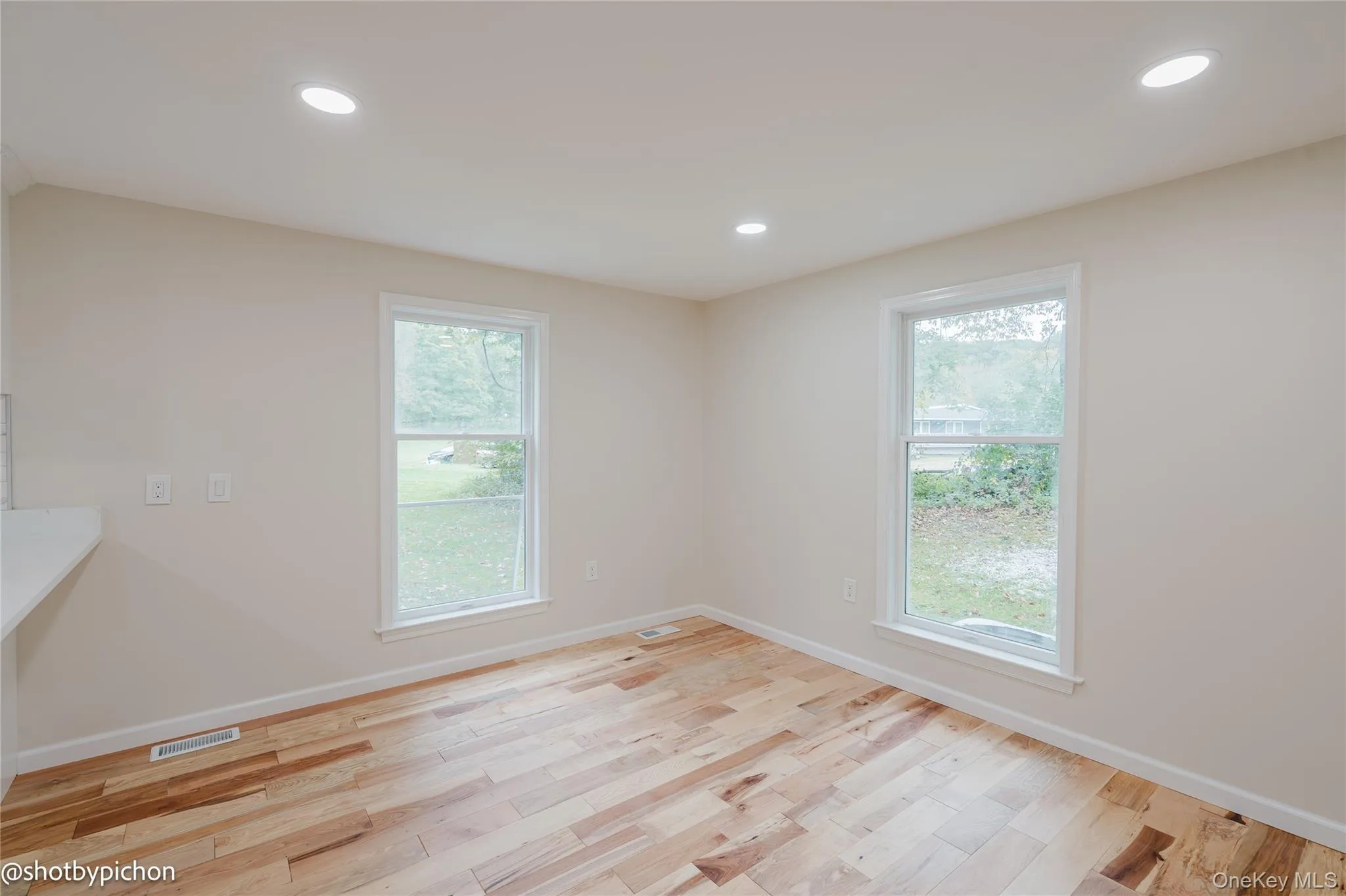Light wood-finish flooring, recessed ceiling lighting, and two double-hung windows Light wood-finish flooring, recessed ceiling lighting, and two double-hung windows