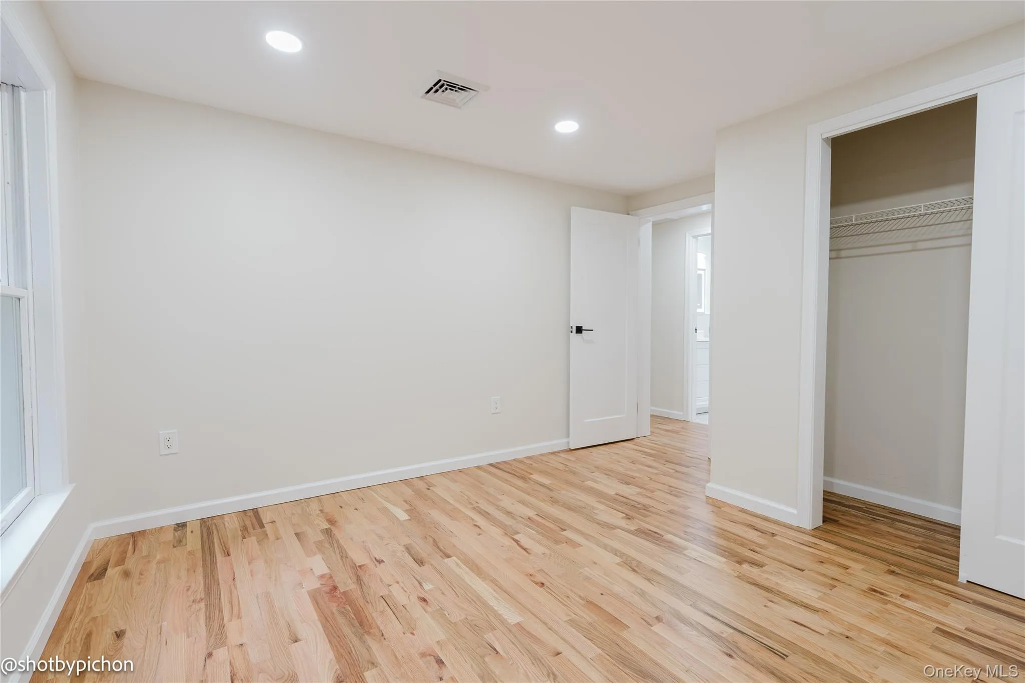 Wood-finish flooring, recessed lighting, and a window with white trim Wood-finish flooring, recessed lighting, and a window with white trim