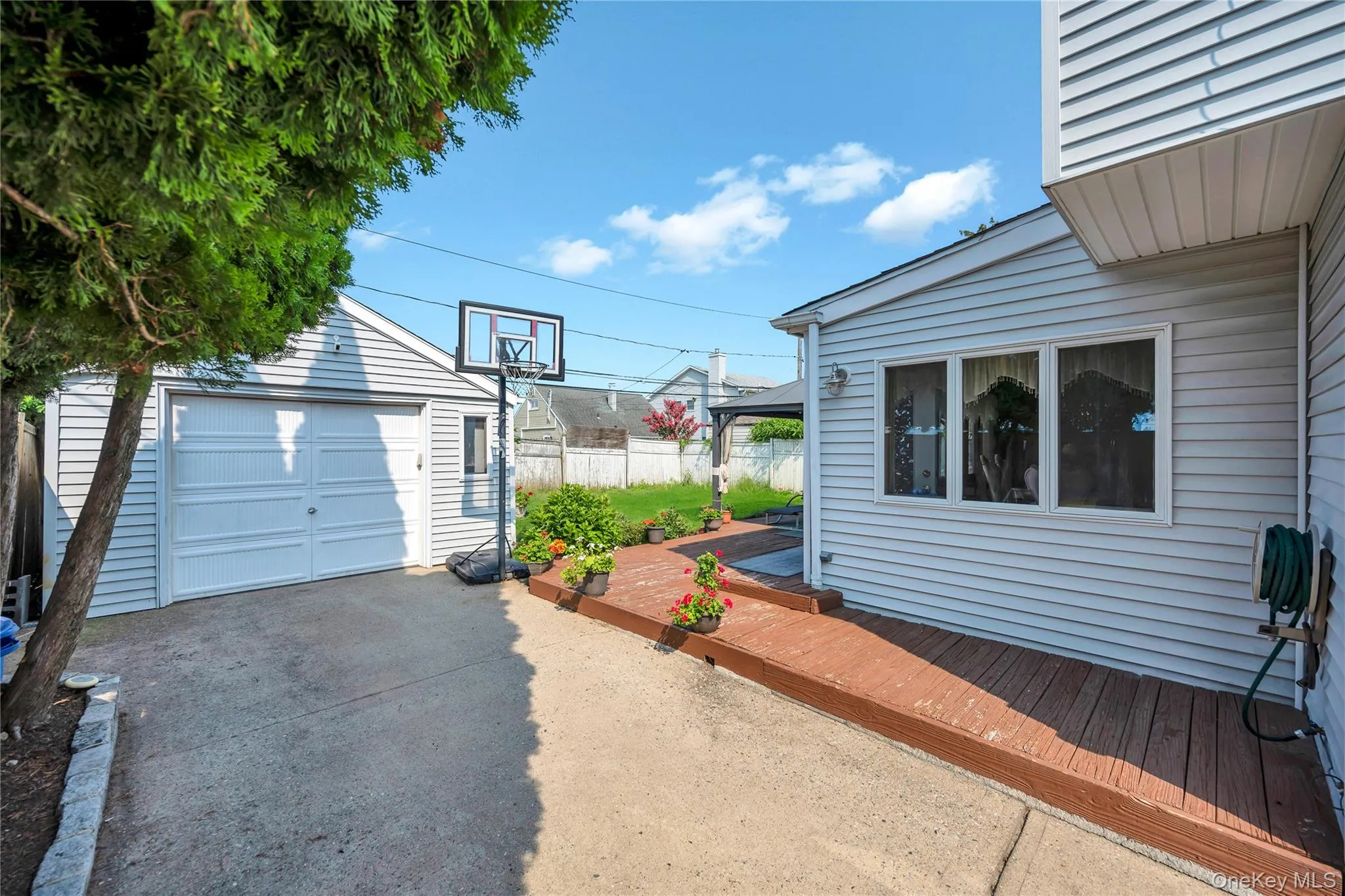 Detached garage with horizontal siding, concrete driveway, wood-look decking, and multiple exterior windows Detached garage with horizontal siding, concrete driveway, wood-look decking, and multiple exterior windows