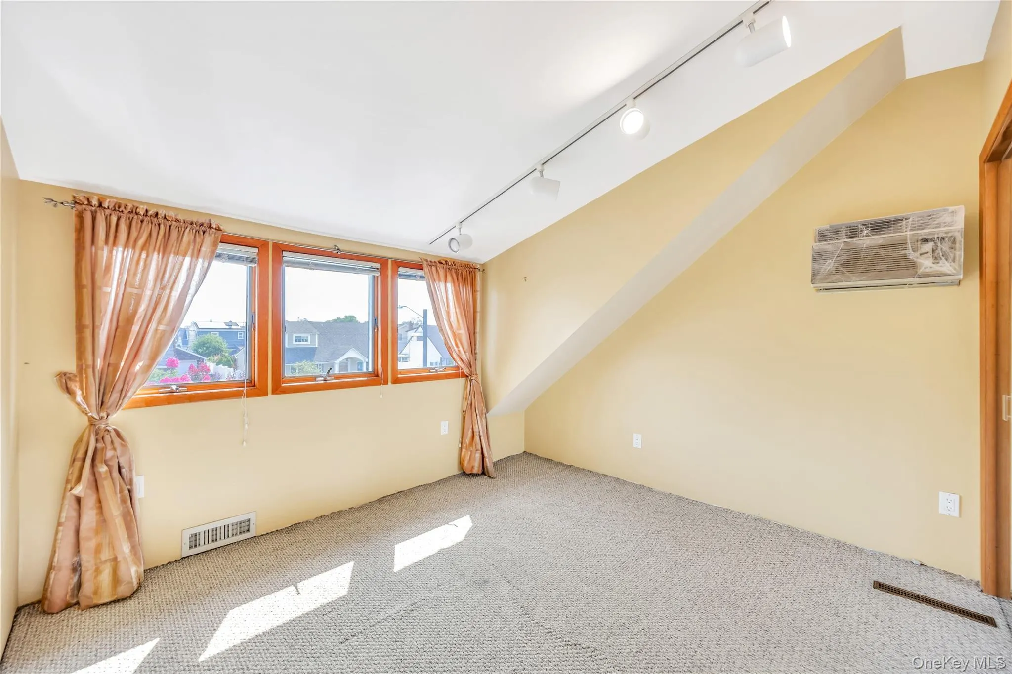 Carpeted spare room with rail lighting and an AC wall unit Carpeted spare room with rail lighting and an AC wall unit
