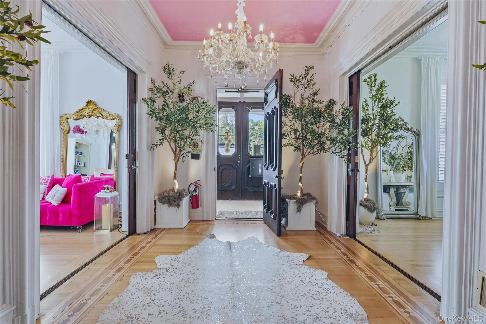 Grand entryway featuring a decorative chandelier, dual paneled doors, and light wood-finish flooring with intricate inlay Grand entryway featuring a decorative chandelier, dual paneled doors, and light wood-finish flooring with intricate inlay